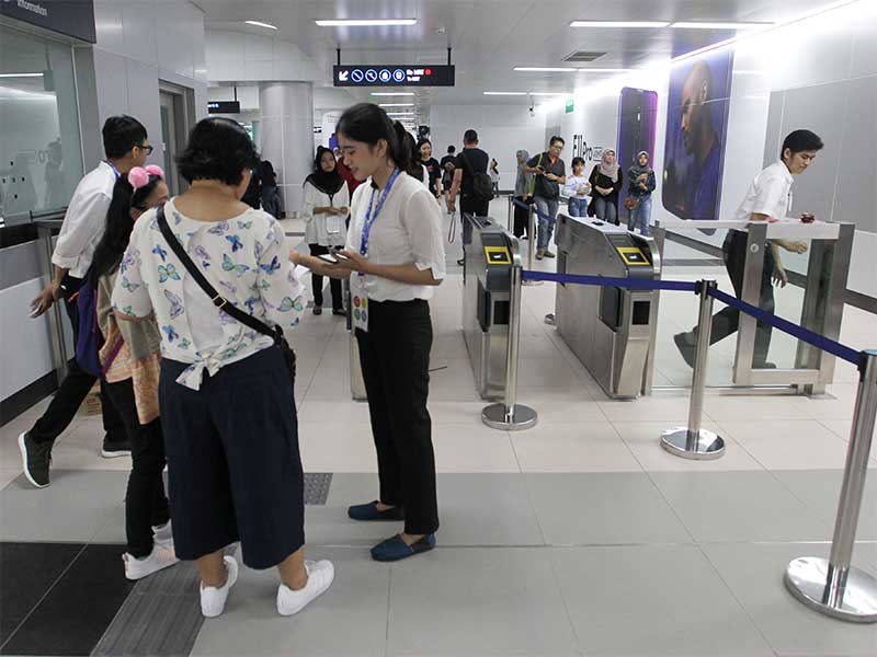Petugas membantu warga yang akan menaiki Moda Raya Terpadu (MRT) dengan cara menunjukkan bukti pendaftaran saat akan mengikuti uji coba publik MRT di Stasiun Bundaran HI, Jakarta, Minggu (17/3).