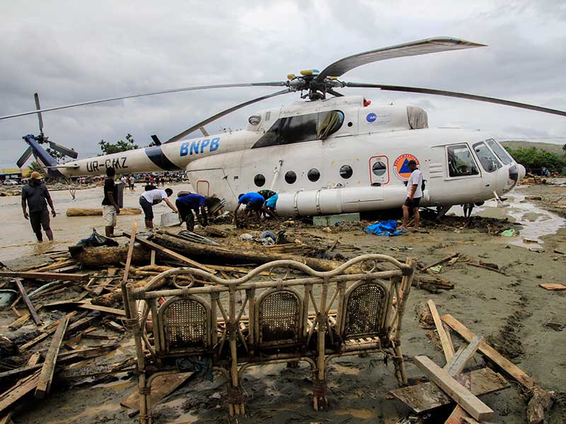 Warga berada di dekat helikopter milik BNPB yang bergeser dari tempatnya akibat banjir bandang di Sentani, Kabupaten Jayapura, Papua, Minggu (17/3/2019)