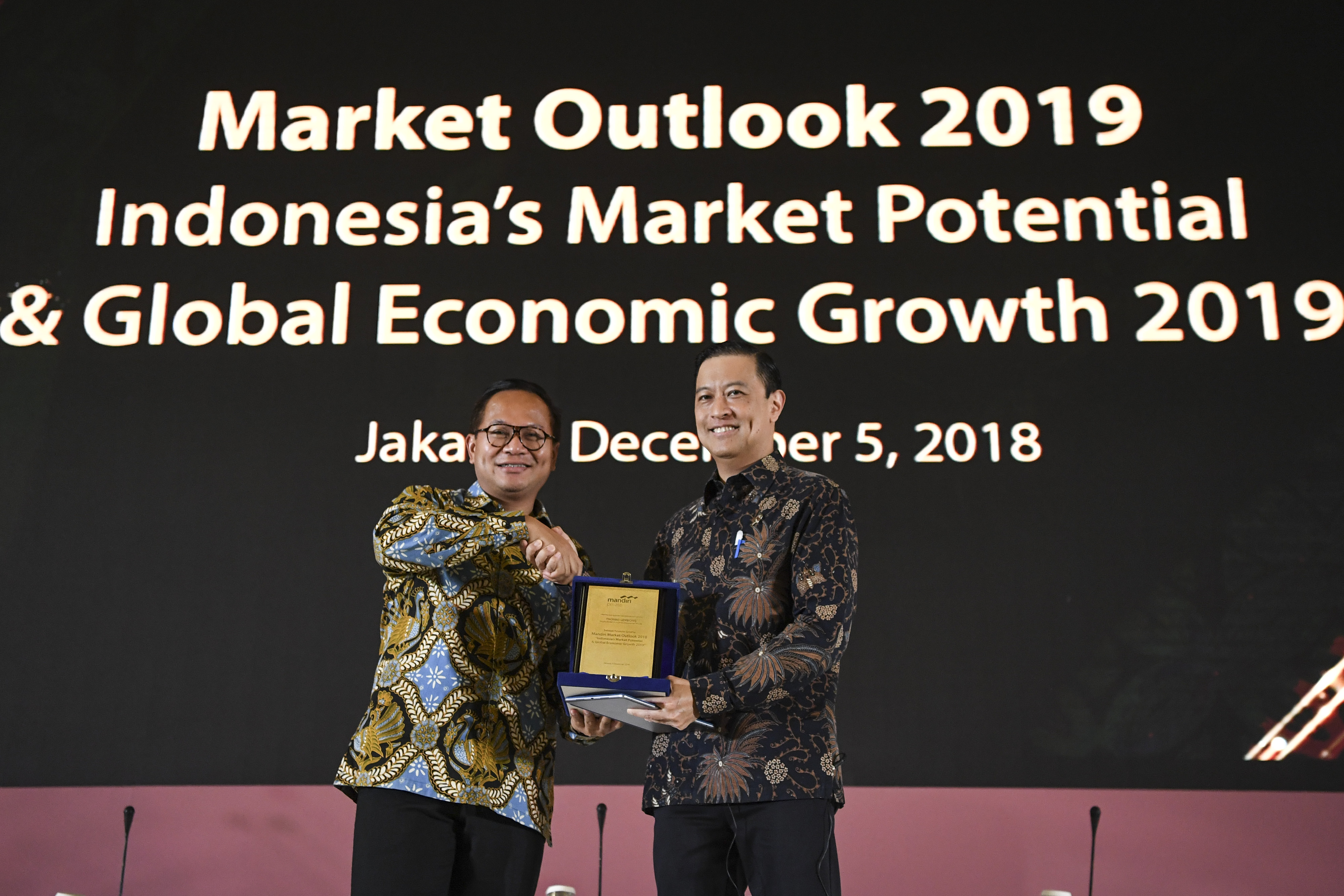 Direktur Utama Bank Mandiri Kartika Wirjoatmodjo (kiri) menyerahkan plakat kepada Kepala BKPM Thomas T Lembong (kanan) saat Mandiri Market Outlook 2019 di Jakarta