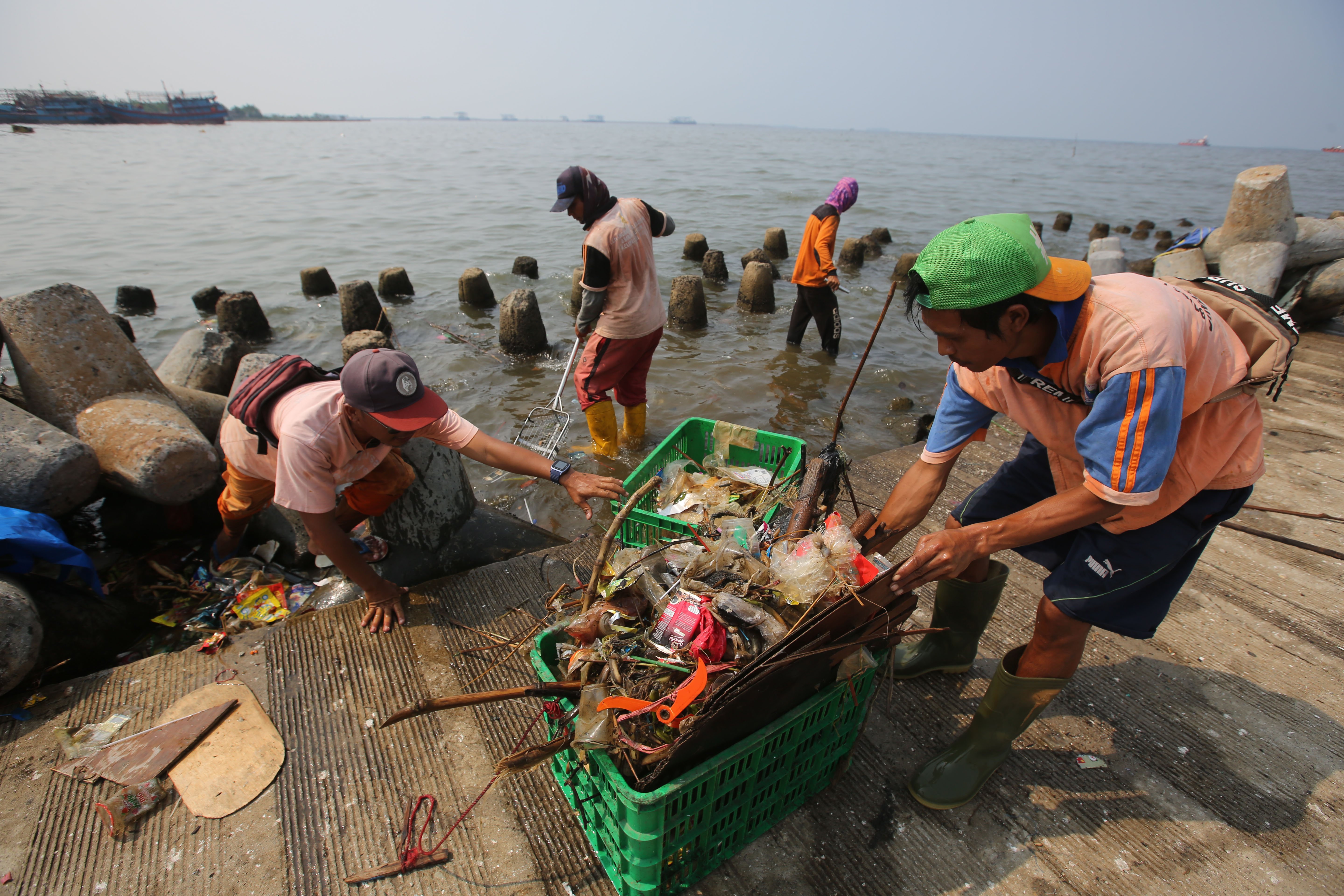 Petugas Suku Dinas Lingkungan Hidup Kepulauan Seribu membersihkan sampah plastik yang terbawa angin Barat Laut di Pelabuhan Kali Adem, Jakar