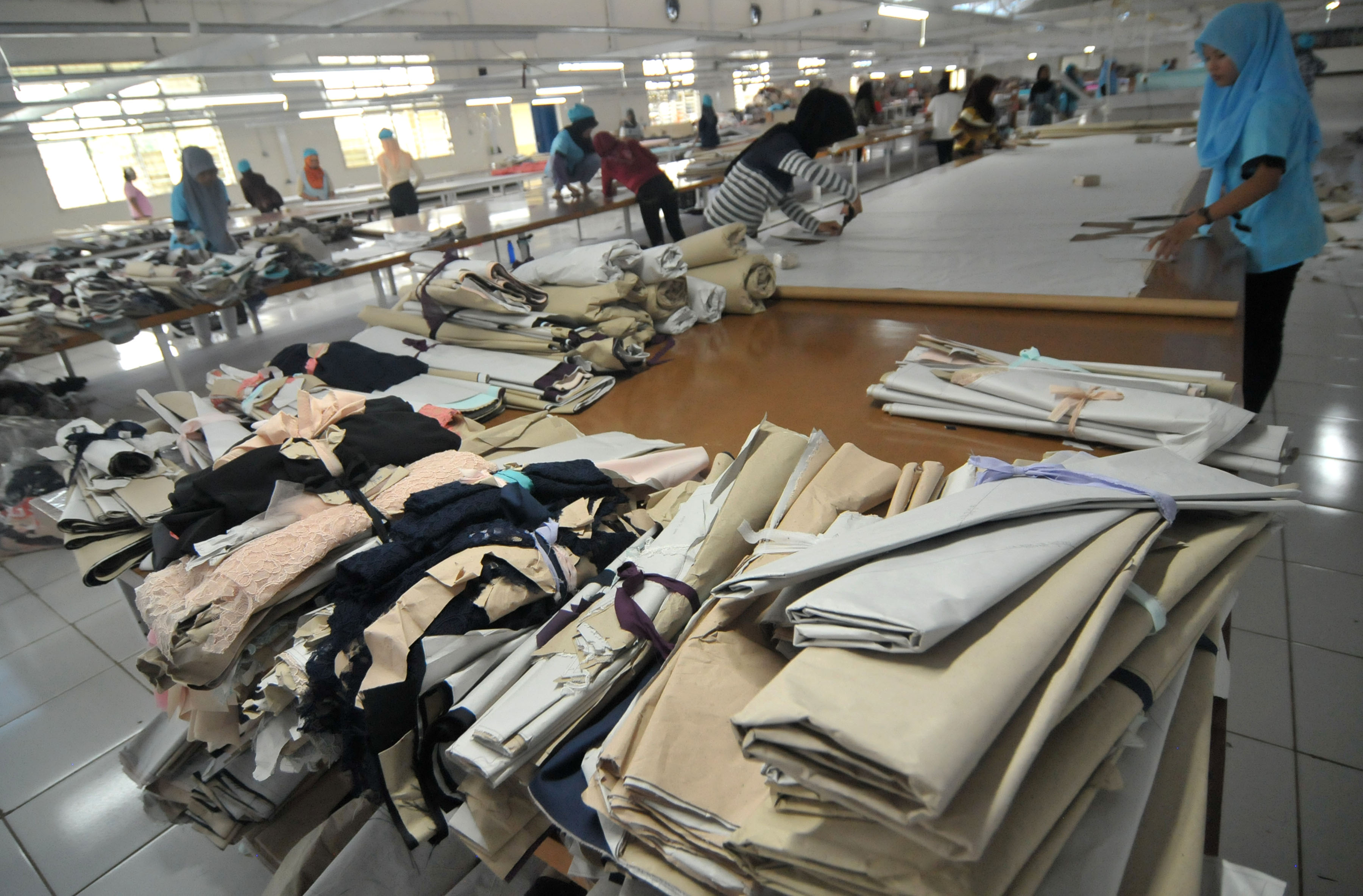 Pekerja menyelesaikan proses pemotongan kain di salah satu industri garmen, Tegal, Jawa Tengah