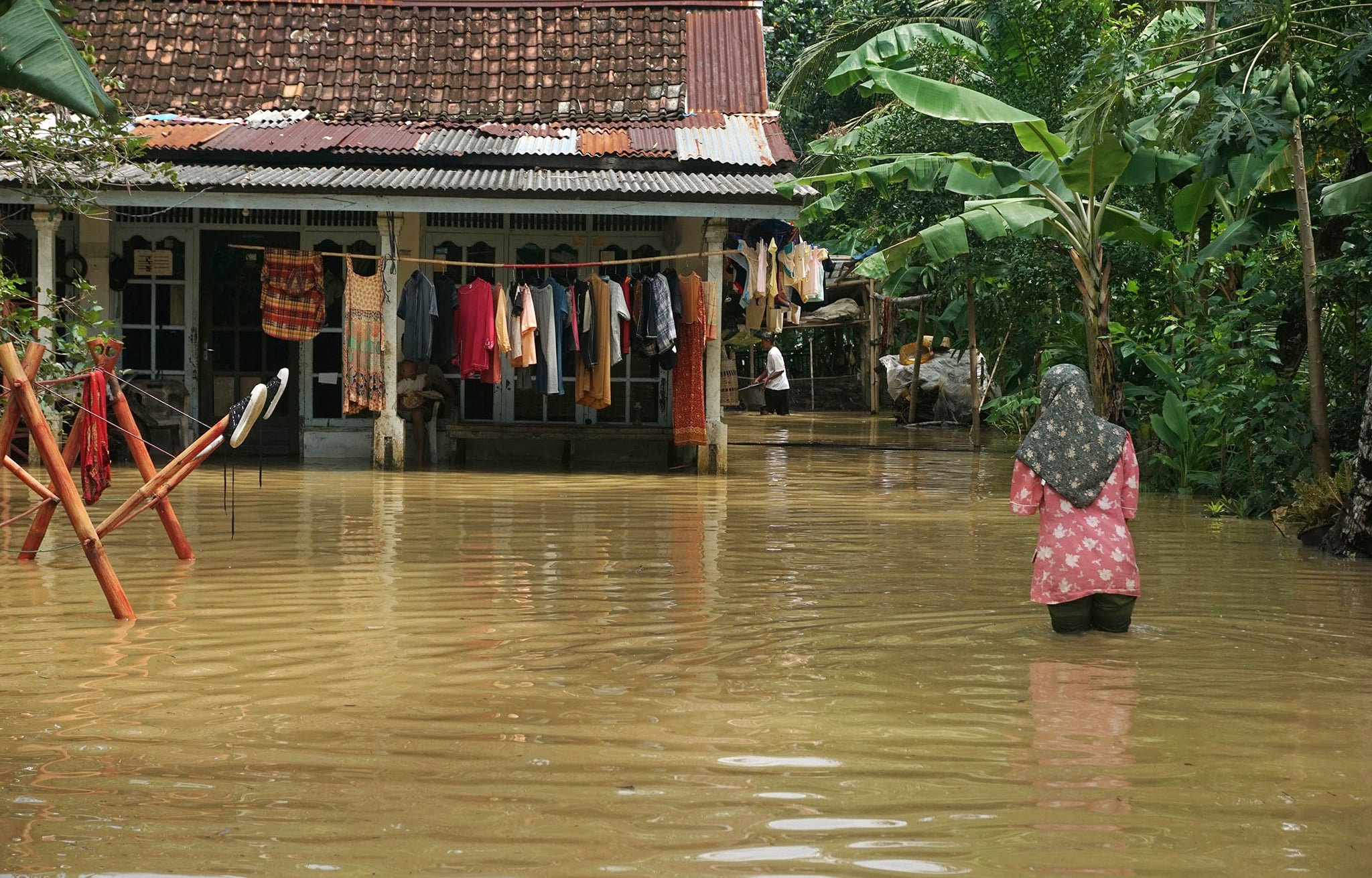 Warga berjalan di tengah banjir yang merendam permukiman penduduk di Desa Mujur Lor, Kroya, Cilacap, Jateng