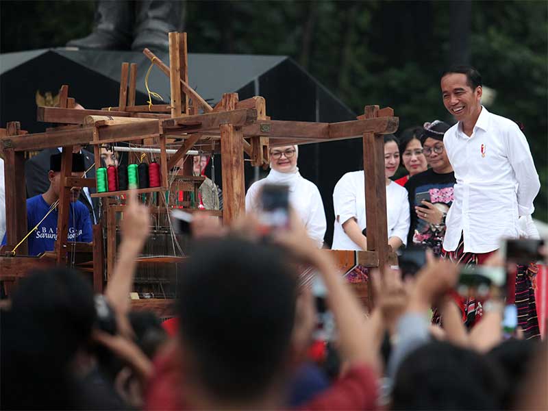 Presiden Joko Widodo didampingi Ibu Negara dan sejumlah pejabat melihat pengrajin menenun kain sarung saat meninjau pelaksanaan acara Sarung Fest 2019 di Plaza Tenggara, Komplek GBK, Senayan, Jakarta, Minggu (3/3). 