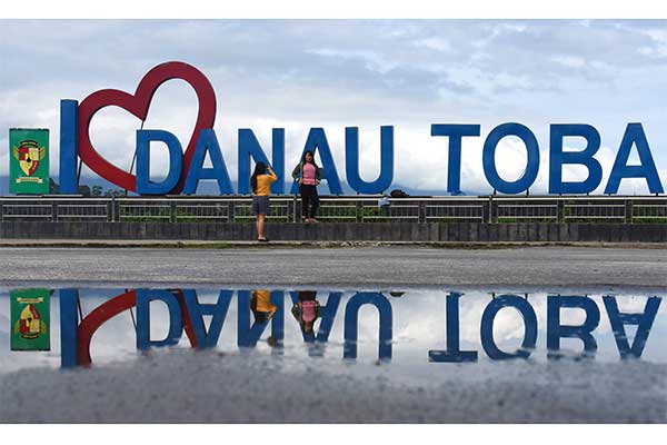 Wisatawan berfoto di di Dermaga Parapat Danau Toba, Simalungun, Sumatera Utara, Minggu (4/11/2018). 