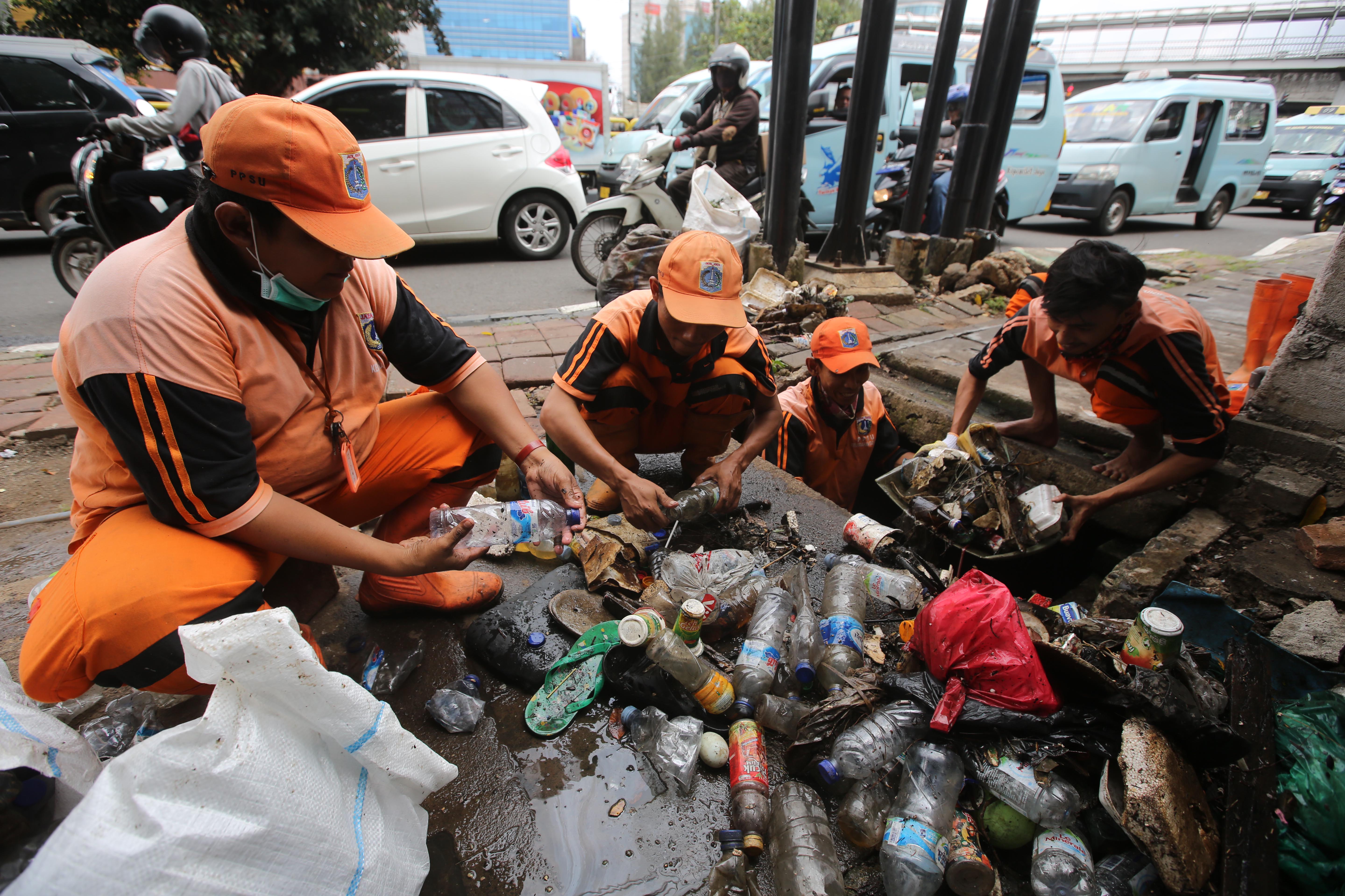 Petugas membersihkan saluran air yang dipenuhi botol plastik di kawasan Slipi, Jakarta, Selasa (15/1). 