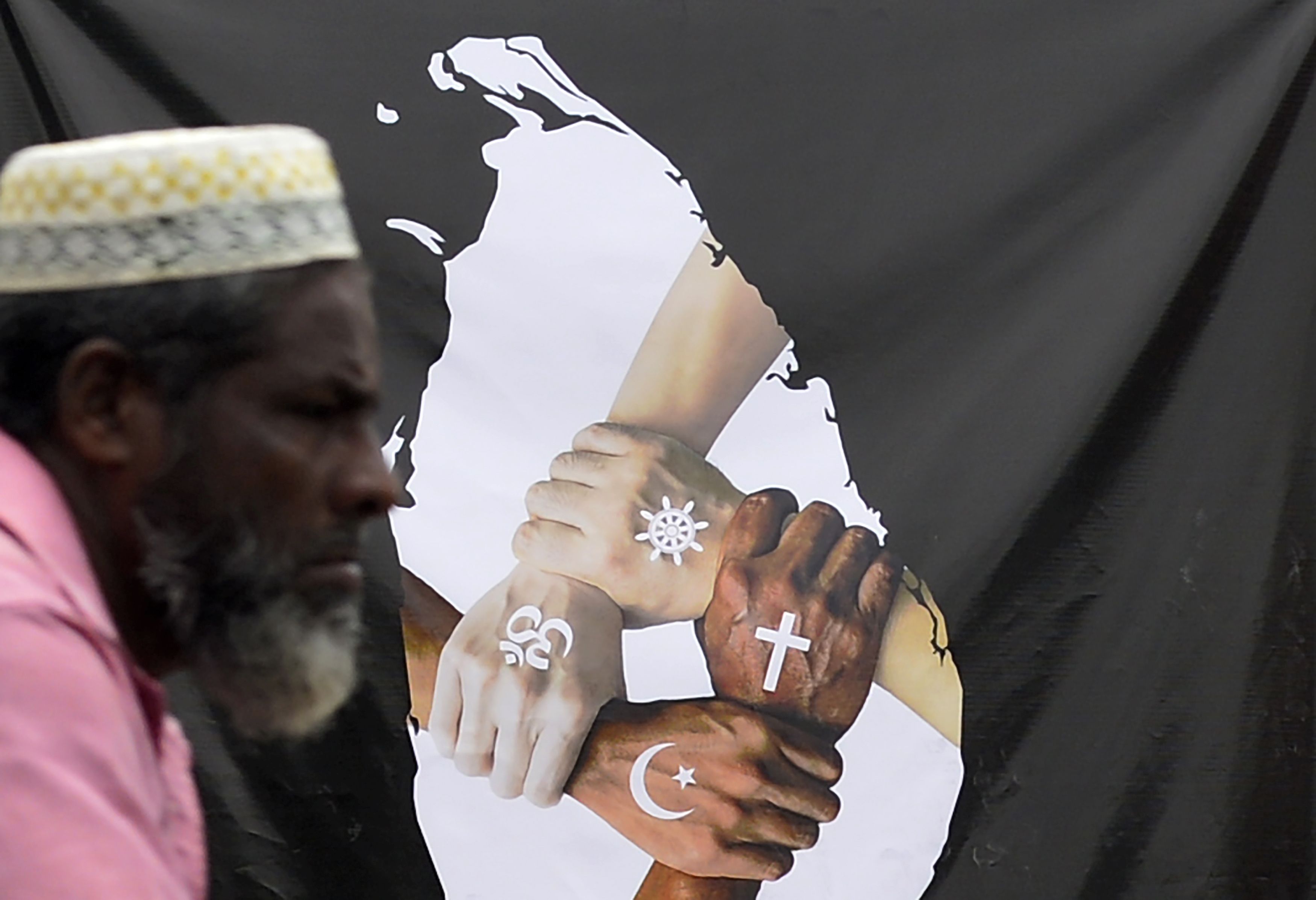 Seorang warga melewati sebuah poster yang menggambarkan persatuan antar agama.