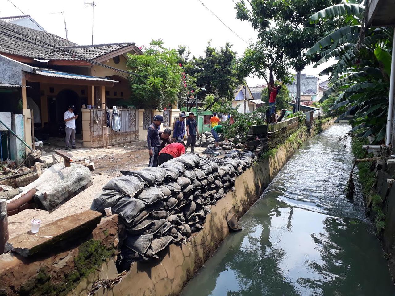 Ratusan karung pasir dipasang di pinggir kali Perumahan Cahaya Kemang Permai, Bekasi, pada Senin (1/4/2019).