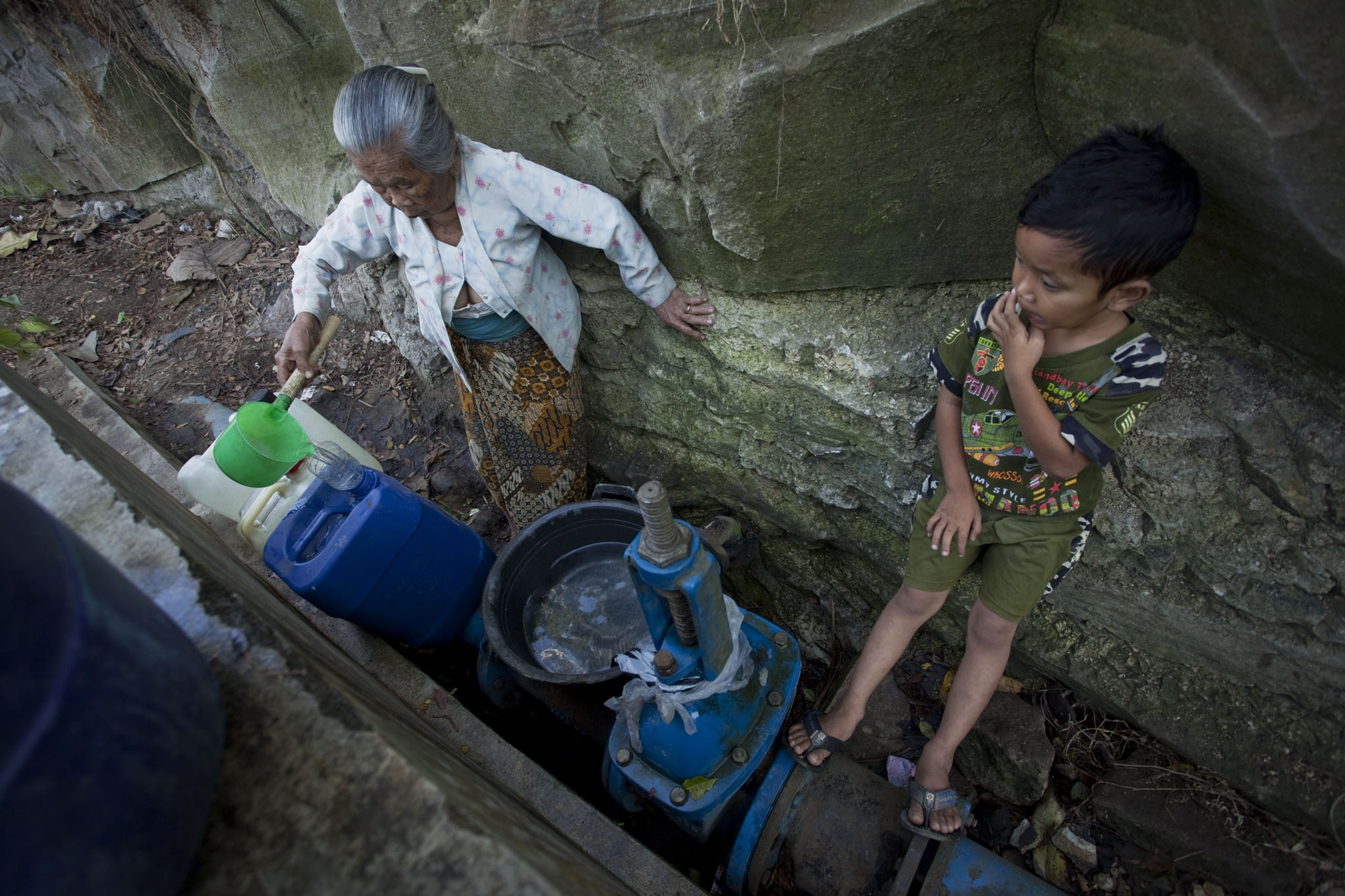 Seorang nenek memasukkan ke dalam jerigen, air hasil tampungan rembesan pipa saluran air 