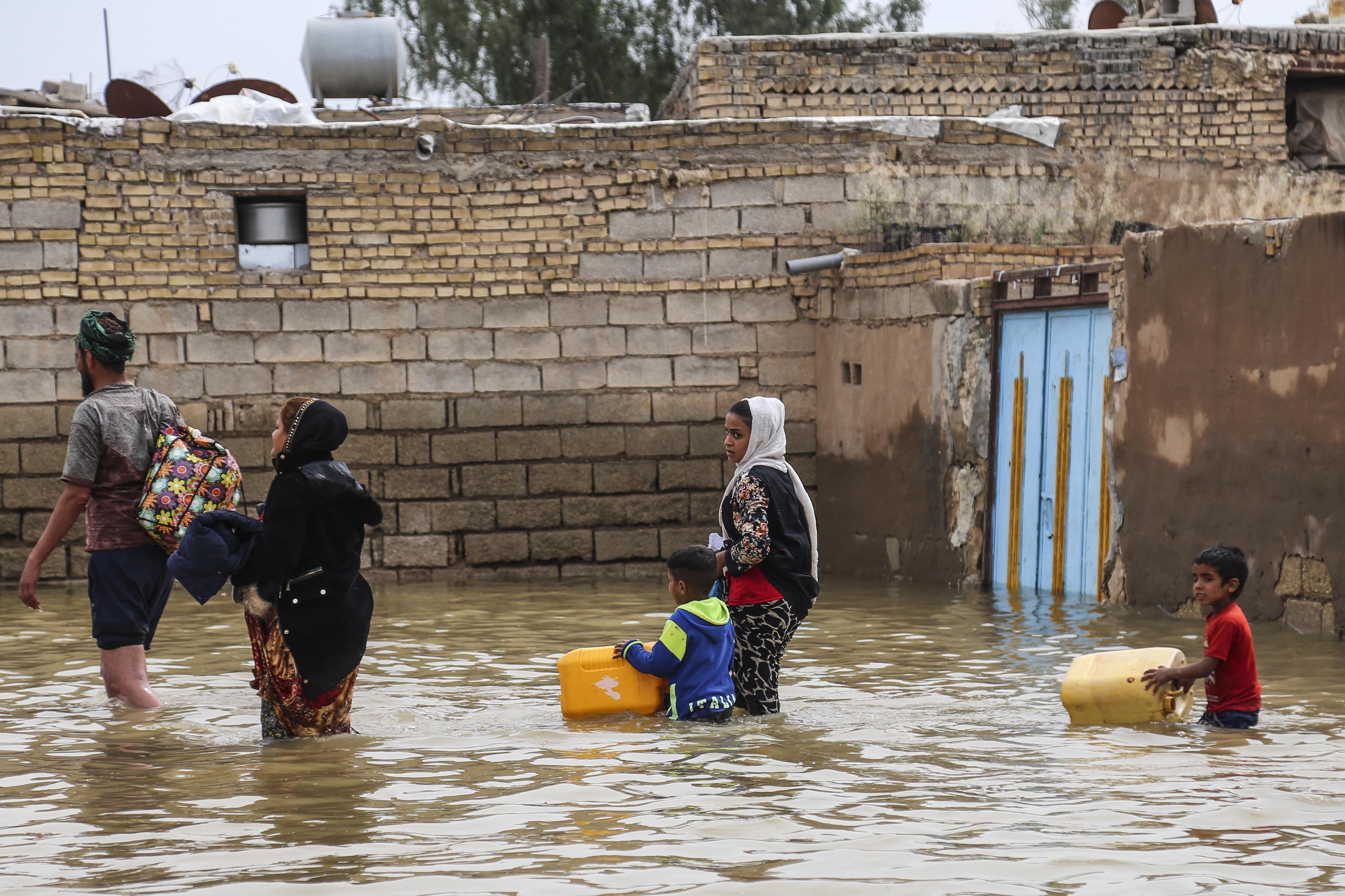 Sejumlah warga Iran berjalan di jalan yang dilanda banjir di Kota Ahvaz, Provinsi Khuzestan, Iran, Minggu (31/3).