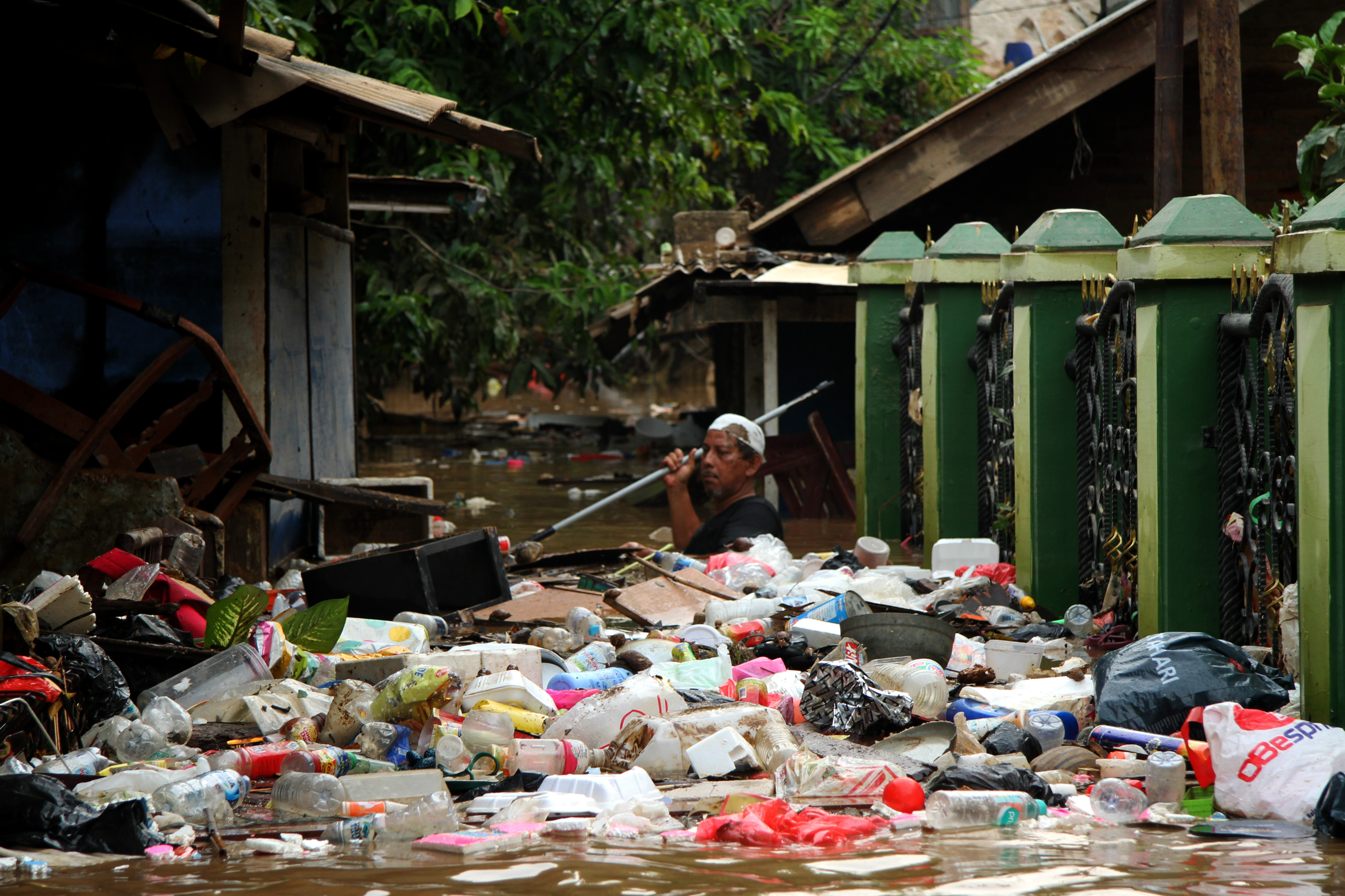 Seorang warga berusaha membersihkan sampah yang terbawa aliran banjir di kawasan permukiman penduduk Cililitan Kecil, Jakarta.