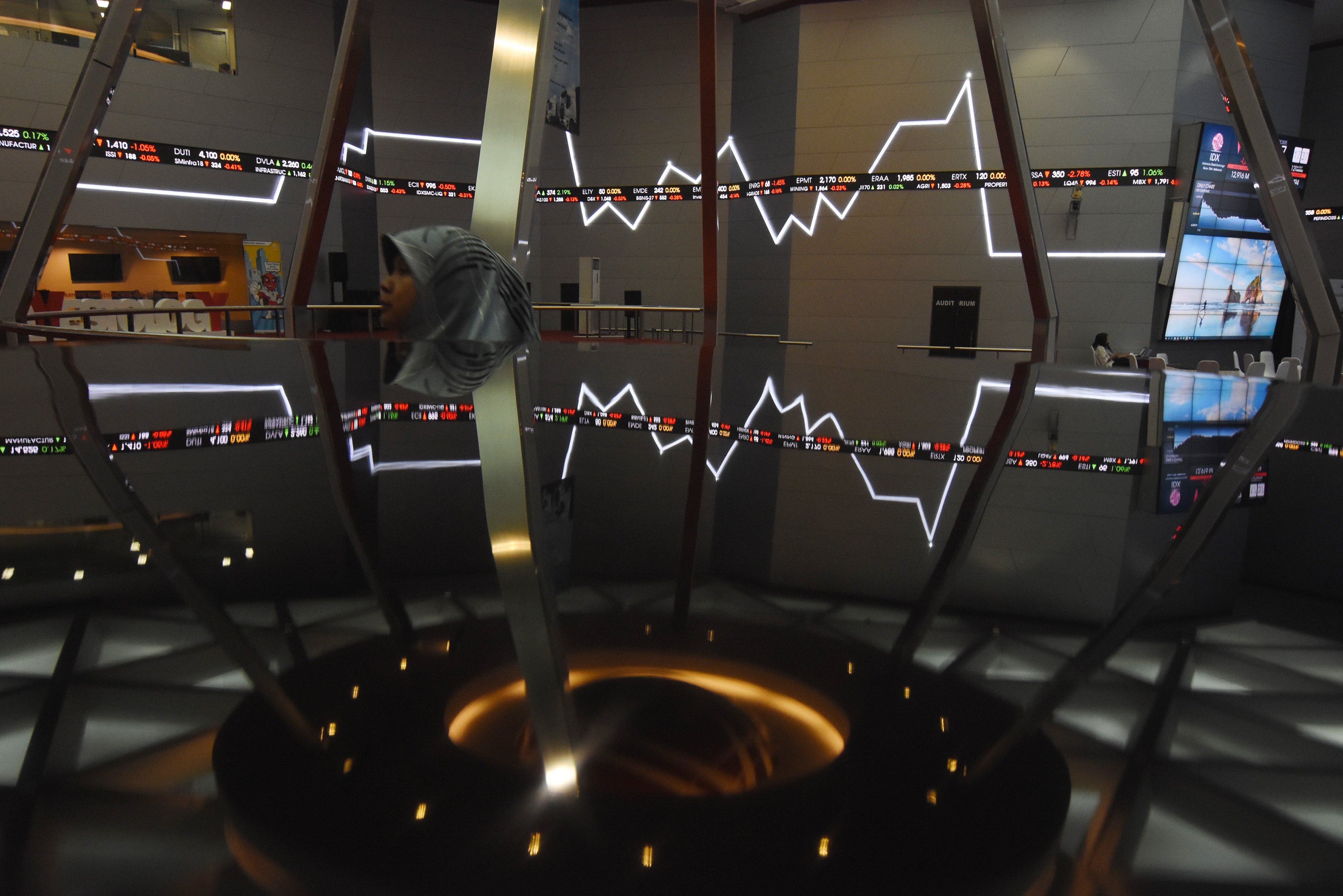  Karyawan melintas di dekat layar pergerakan saham di Bursa Efek Indonesia, Jakarta, beberapa waktu lalu.