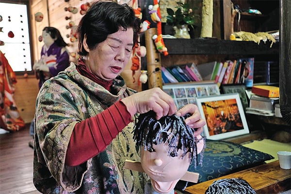 Tsukimi Ayano sedang membuat rambut yang terbuat dari wol rajut.