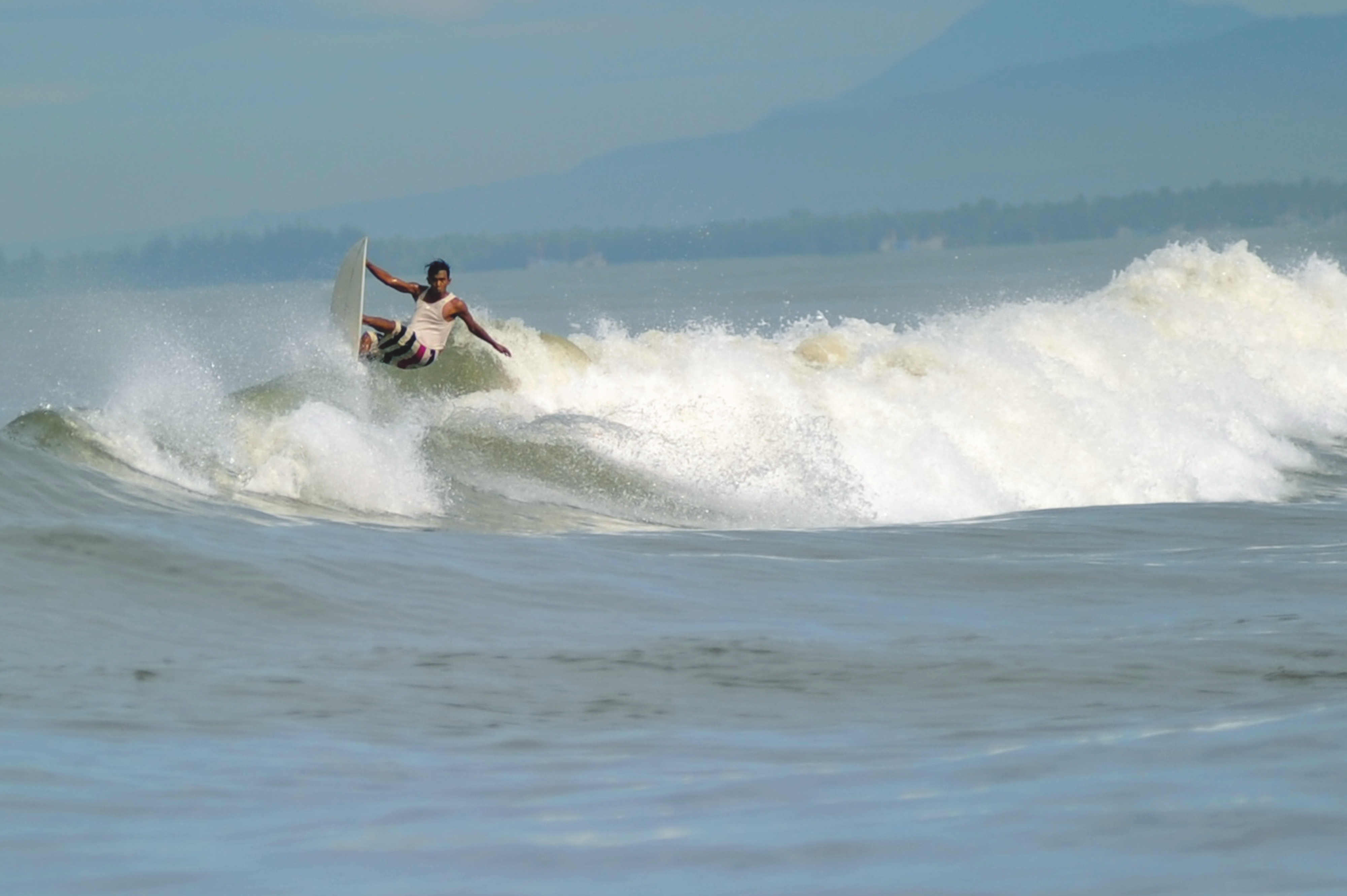 Peselancar memanfaatkan gelombang tinggi di pantai Padang, Sumatera Barat.