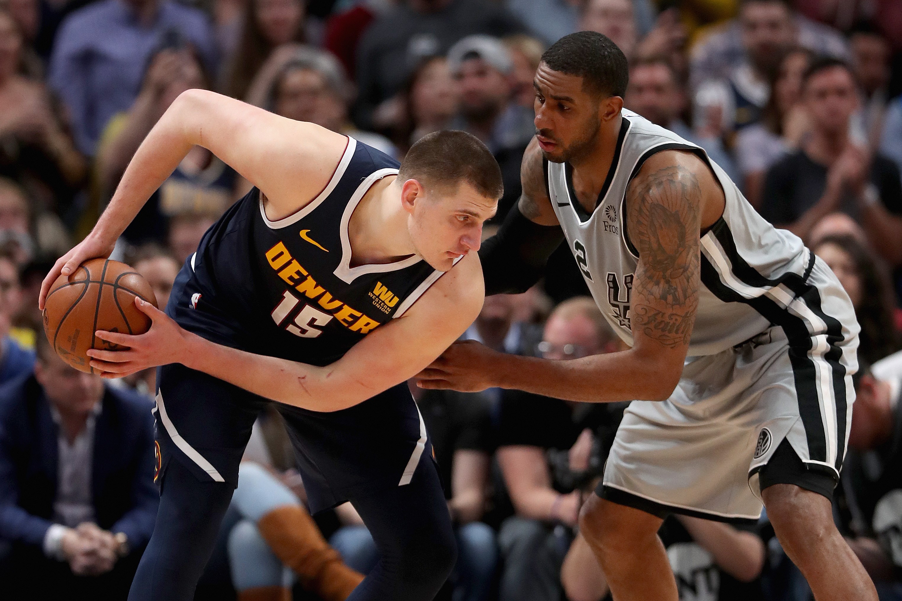Nikola Jokic # 15 dari Denver Nuggets dijaga oleh Lamarcus Aldridge # 12 dari San Antonio Spurs