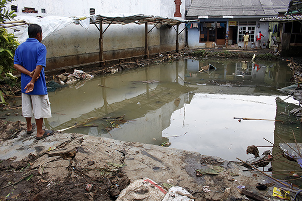 Warga melihat halaman rumahnya yang terggenang air dan lumpur pascajebolnya tanggul aliran Kali Pulo 
