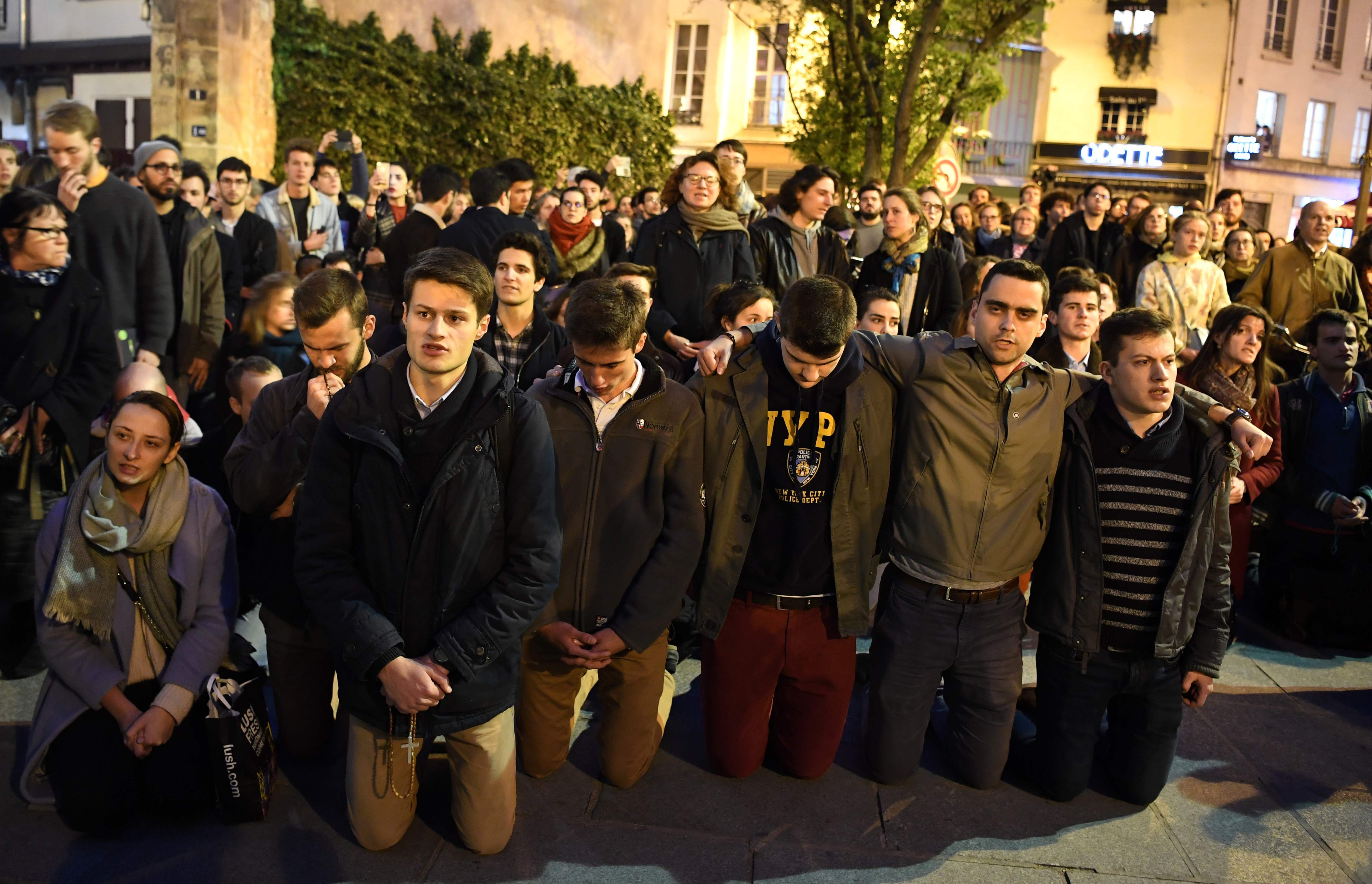 Warga berlutut di dan berdoa saat melihat kebakaran yang melanda Katedral Notre Dame.