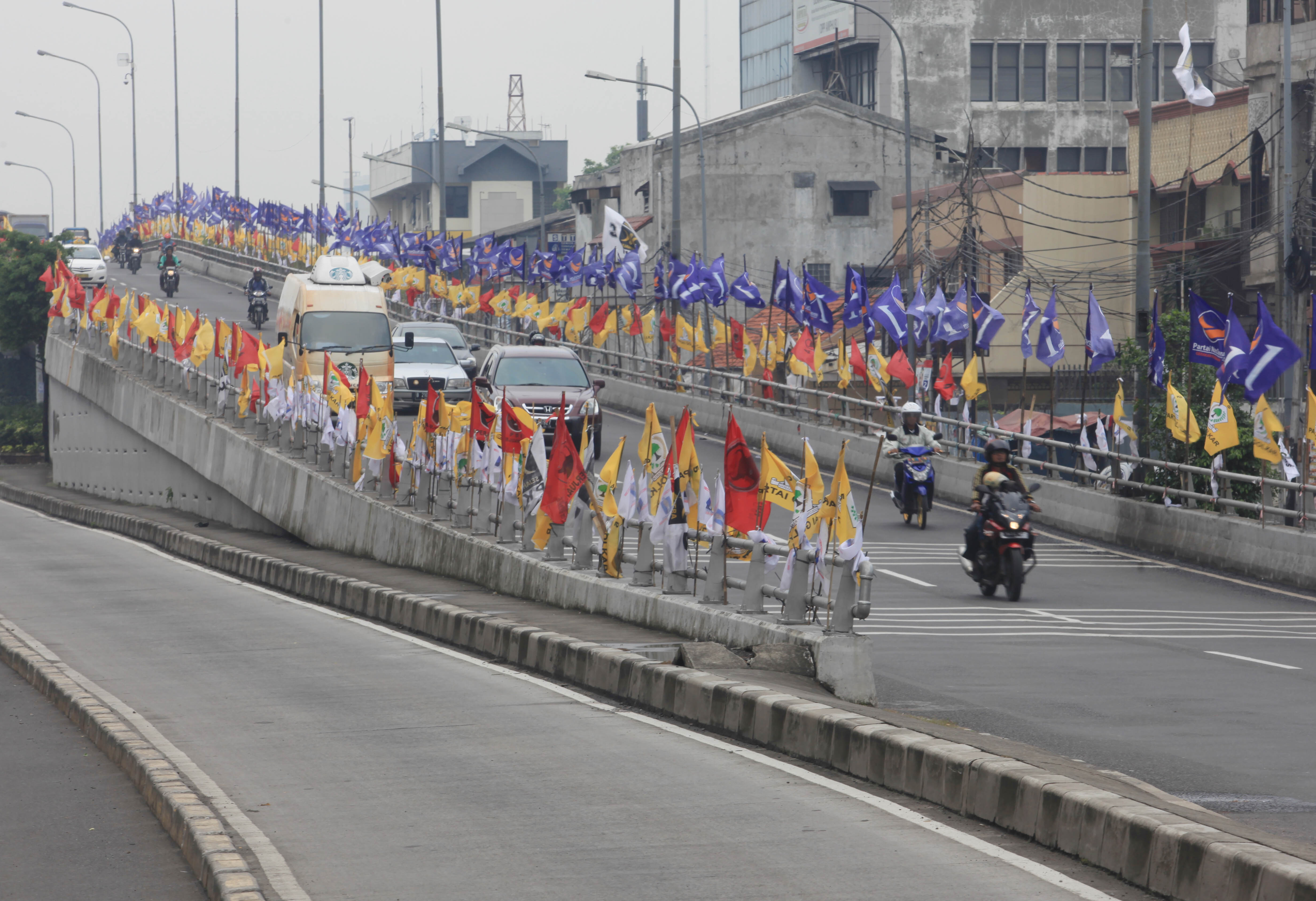 Sejumlah pengendara motor melintasi bendera-bendera parpol di sepanjang sisi jalur jalan layang di Jakarta, beberapa waktu lalu.