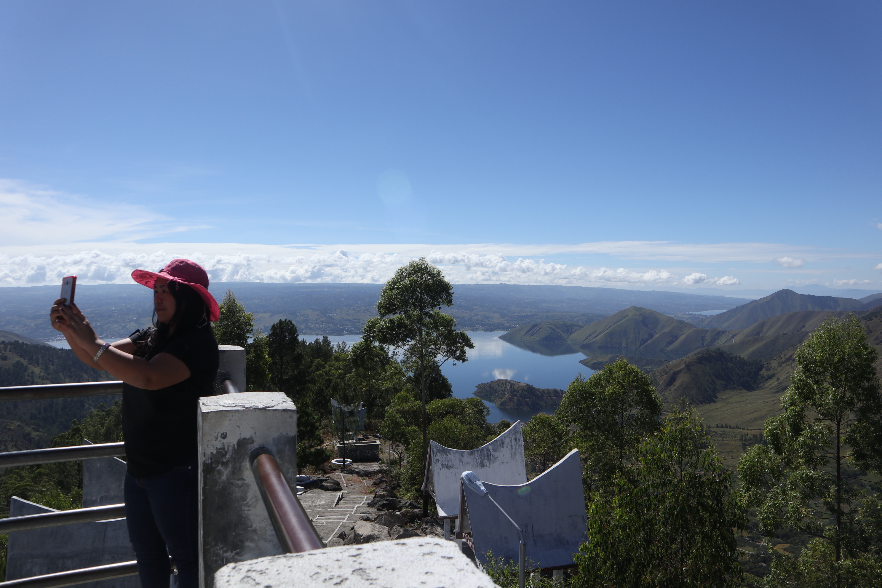 Seorang wisatawan berswafoto di Menara Pandang Tele dengan latar belakang kaldera Danau Toba.