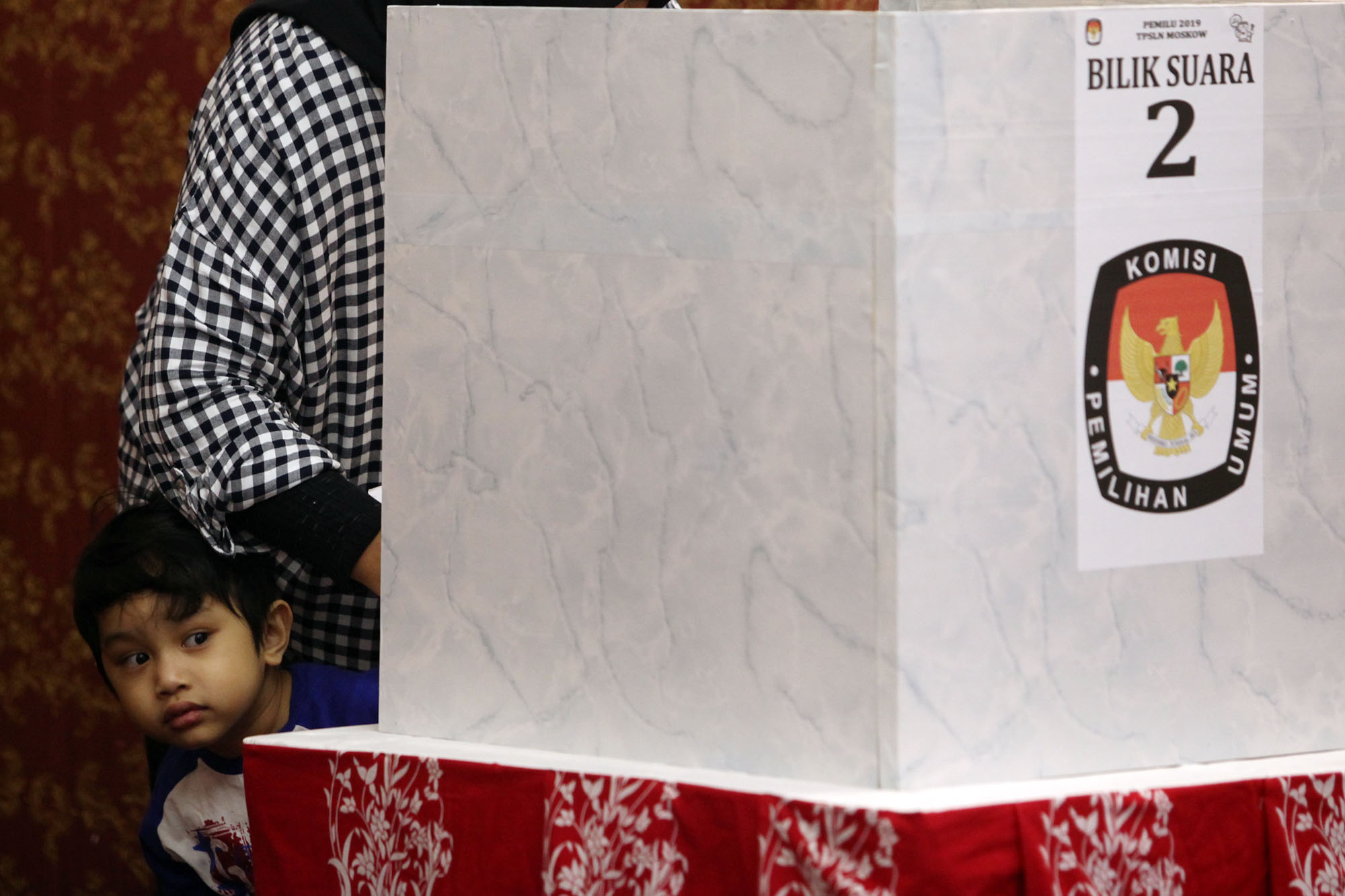 Seorang anak menemani ibunya saat menggunakan hak pilihnya di Tempat Pemungutan Suara Luar Negeri 