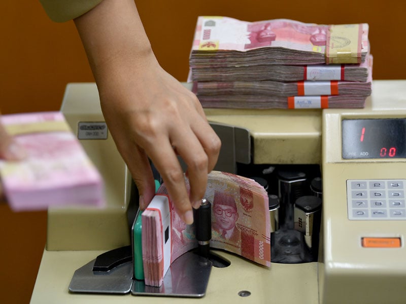 Karyawan menghitung mata uang rupiah di gerai penukaran mata uang asing