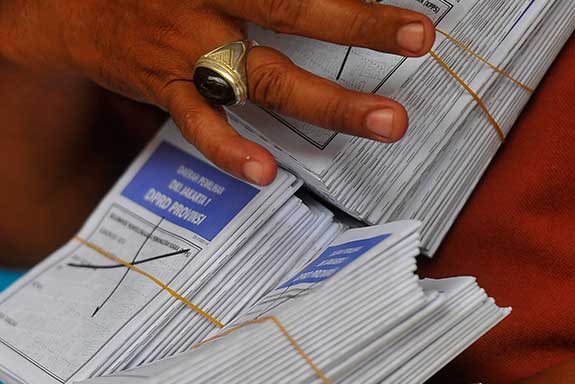 Petugas KPPS memperlihatkan kertas suara yang tidak terpakai