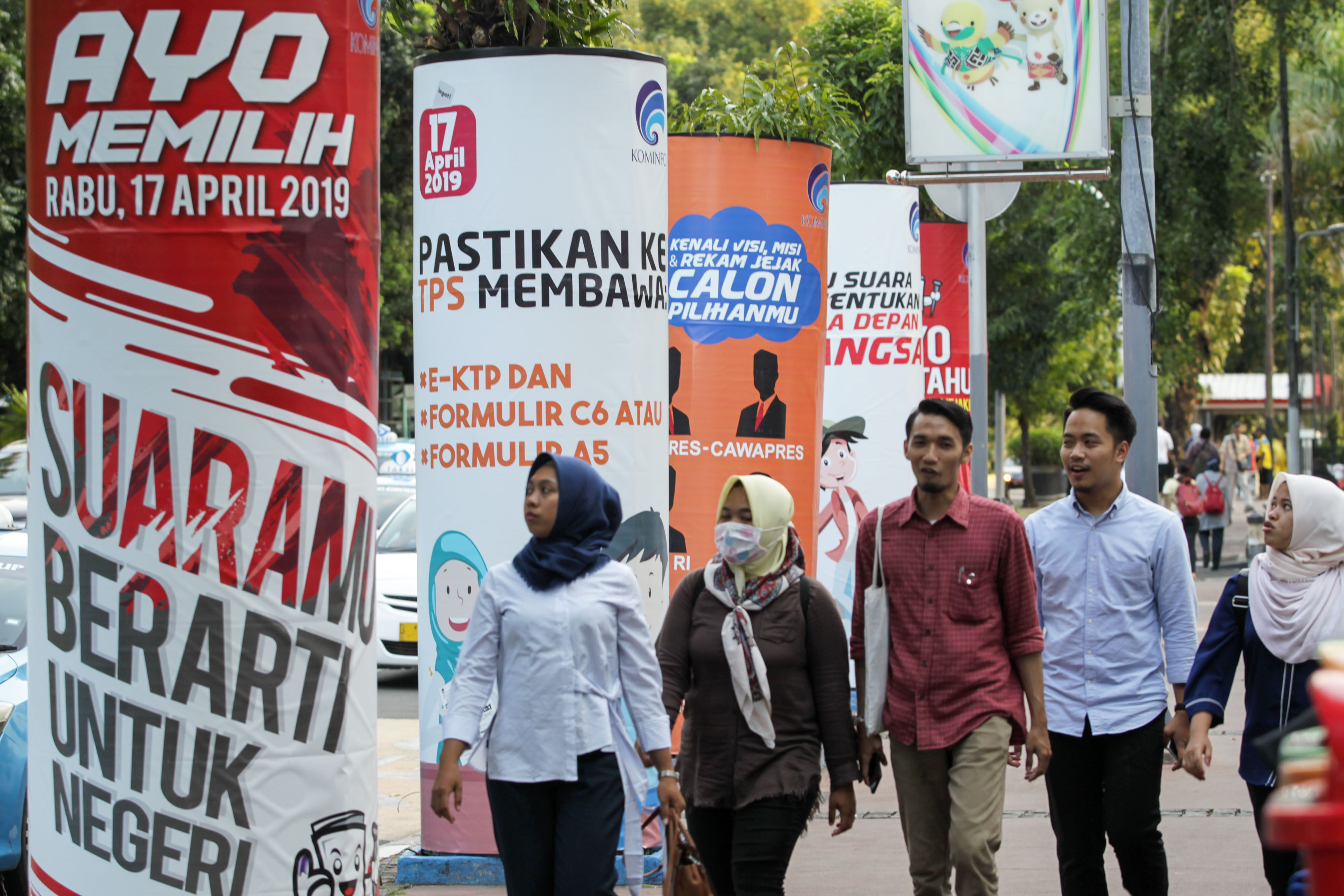 Pejalan kaki melintas media cetak digital berisi informasi Pemilu 2019 di depan Kantor Kemenkominfo, Jakarta, pada Februari 2019.