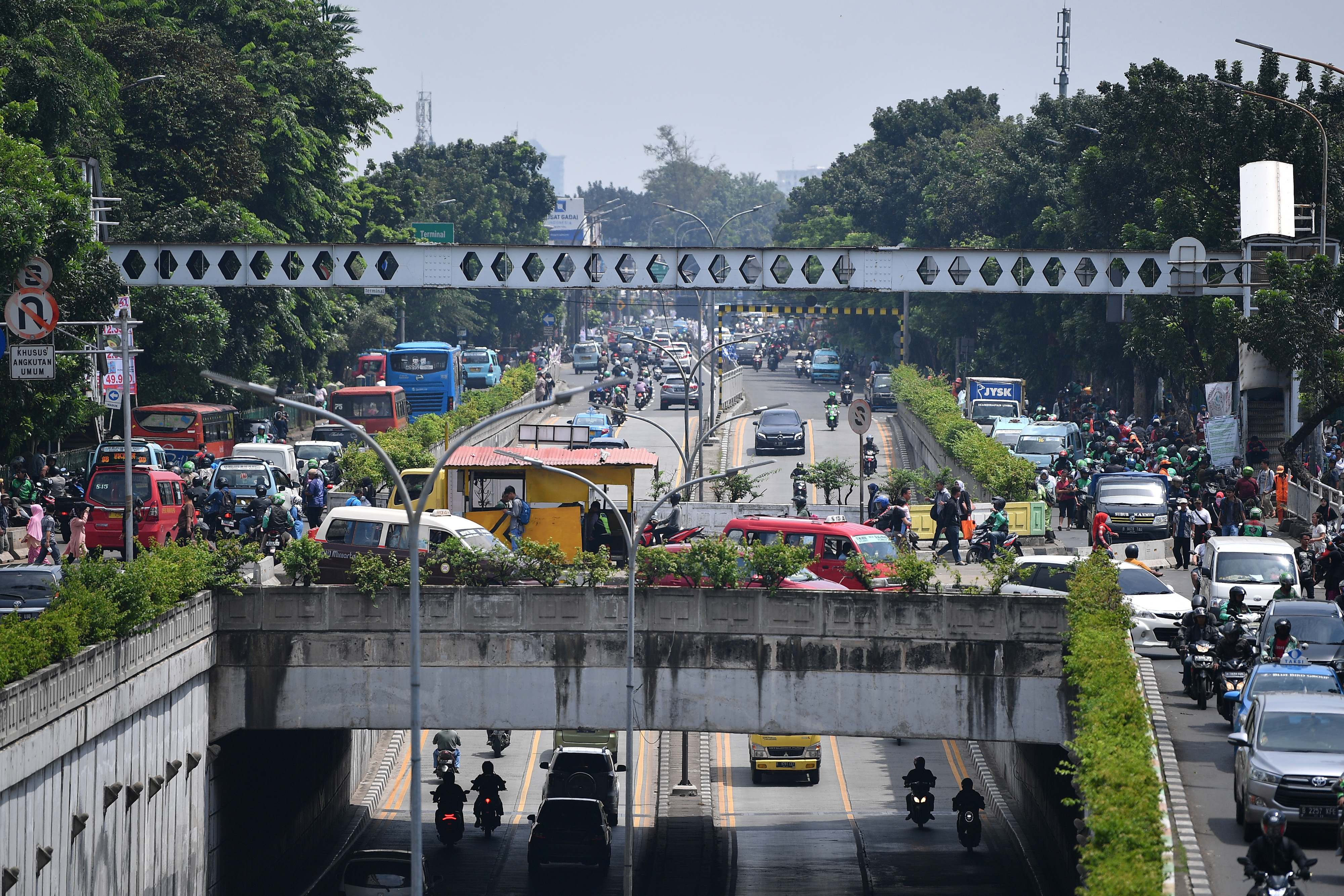 Warga dan kendaraan bermotor melintas di dekat Jembatan Penyeberangan Orang (JPO) yang rusak di Pasar Minggu, Jakarta Selatan.