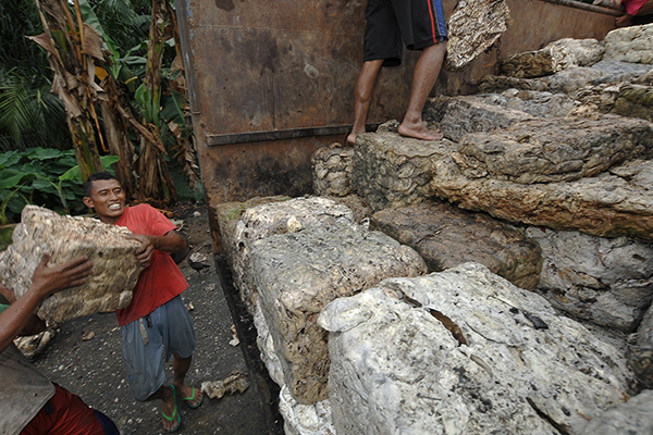 Pekerja memuat getah karet di tempat penampungan karet sementara 