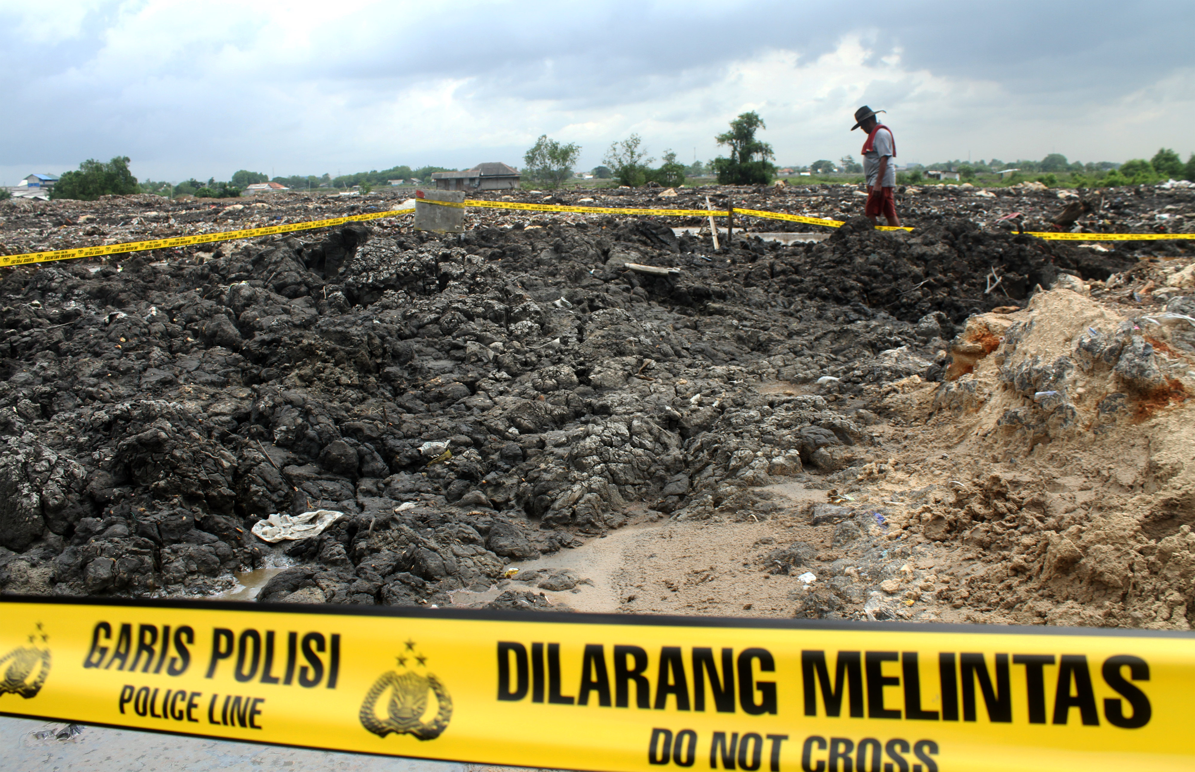 Warga melintas di dekat area lahan pembuangan pasir yang diduga mengandung limbah B3, di kawasan Banjir Kanal Timur, Bekasi.
