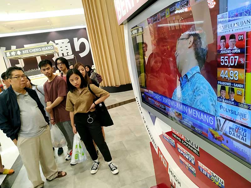 Pengunjung menyaksikan tayangan televisi yang memuat hitung cepat pemilu presiden di sebuah pusat perbelanjaan di Jakarta Barat, Rabu (17/4)