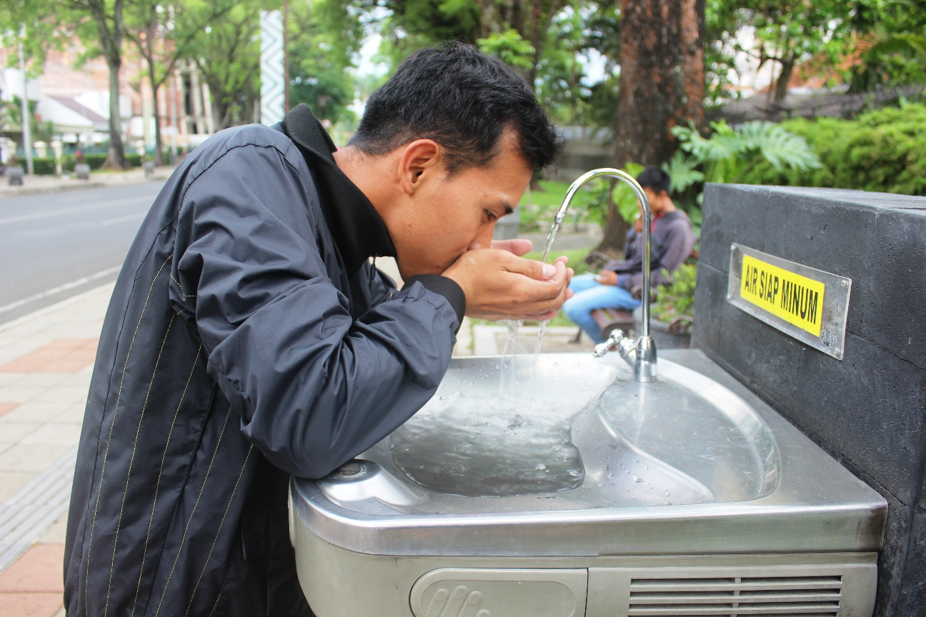  Syamsul, pengunjung dari Pasuruan, Jawa Timur, minum air di fountain tap atau anjungan kran air siap minum di zona air minum prima (ZAMP)