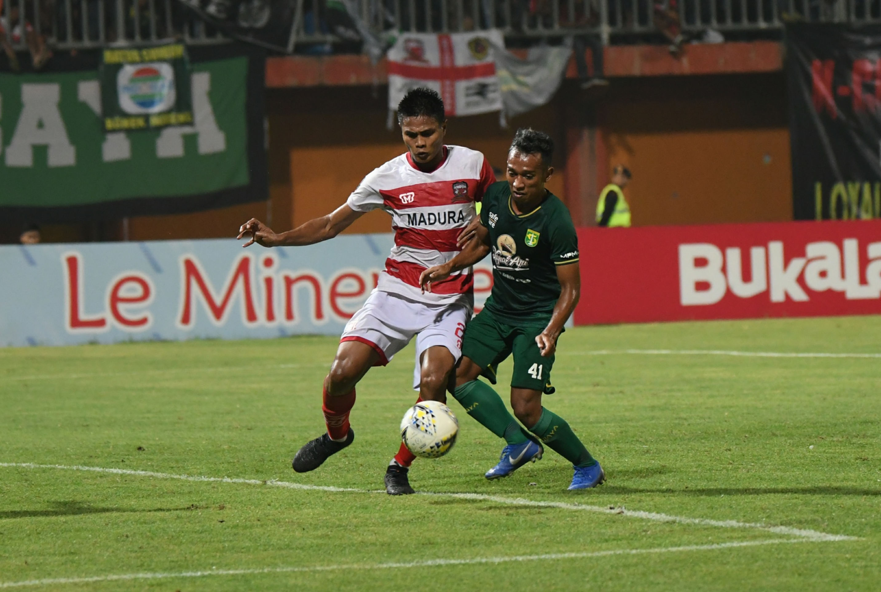  Pesepak bola Persebaya Surabaya Irfan Jaya (kanan) berebut bola dengan pesepak bola Madura United Fakhruddin (kiri)