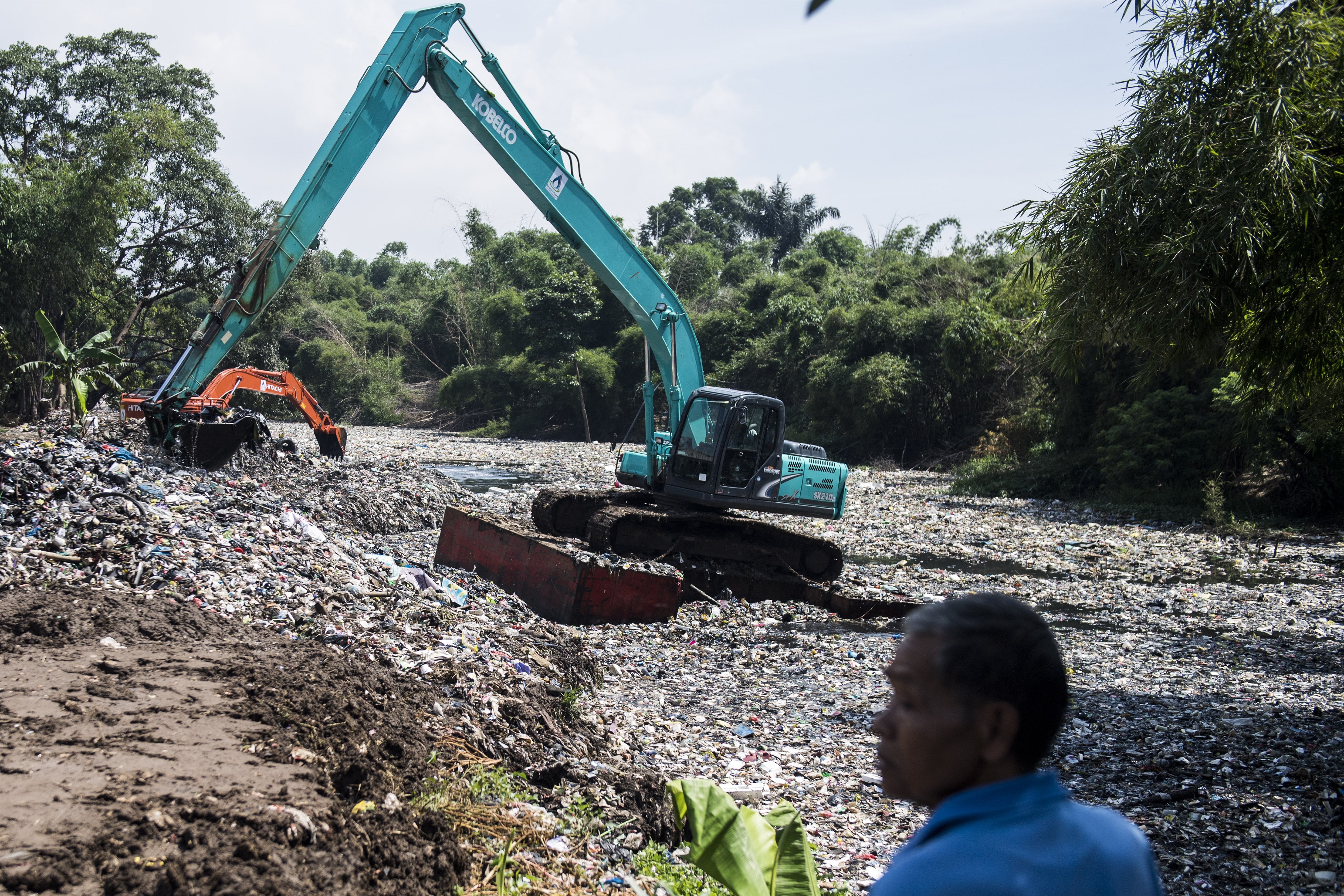  Warga menyaksikan pengerukan sampah dengan eskavator di aliran sungai Citarum lama atau oxbow Cicukang di Kecamatan Margaasih