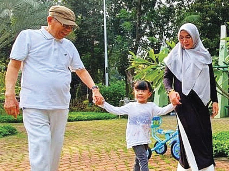 Calon wakil presiden Ma’ruf Amin berjalan bersama istrinya, Wury Estu Handayani (kanan), dan bermain bersama cucunya, Zaitunah (tengah).