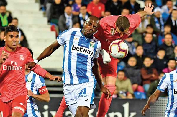 Striker Real Madrid, Karim Benzema (tengah), dan bek Leganes, Allan Nyom, sama-sama berusaha menanduk bola yang melayang di udara