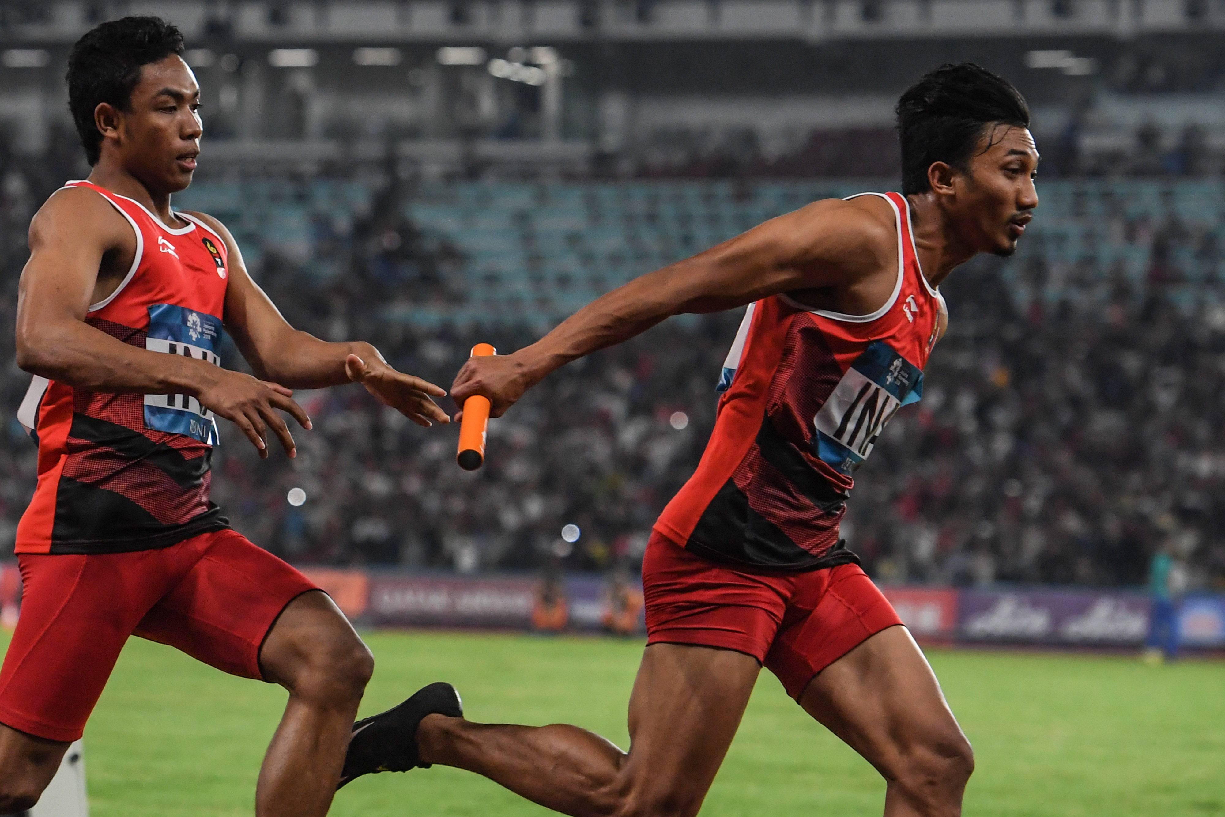 Pelari Indonesia Lalu Muhammad Zohri (kiri) menyerahkan tongkat estafet kepada Eko Rimbawan 