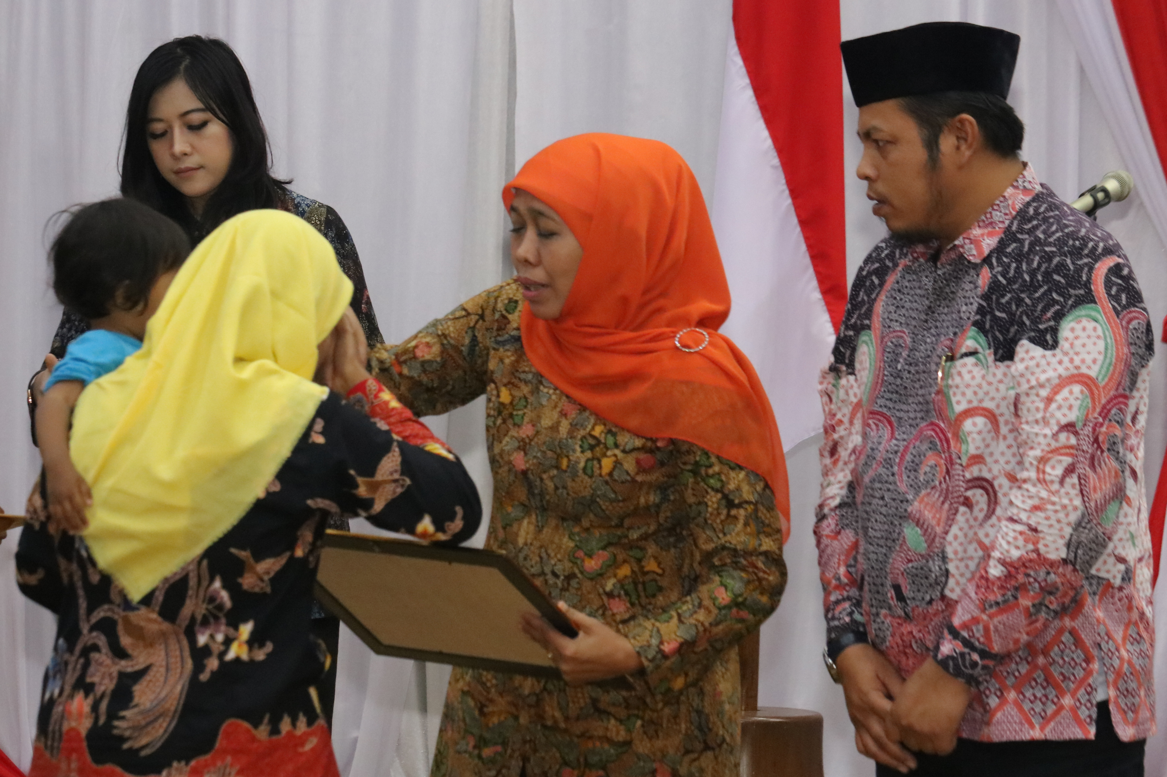 Gubernur Jawa Timur Khofifah Indar Parawansa (kedua kanan) didampingi Ketua KPU Jawa Timur Choirul Anam (kanan) menyerahkan santunan