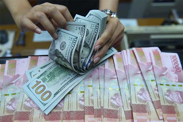  Pekerja menghitung uang Dollar Amerika Serikat dan Rupiah di sebuah tempat penukaran uang di Jakarta, Kamis (28/3/2019).