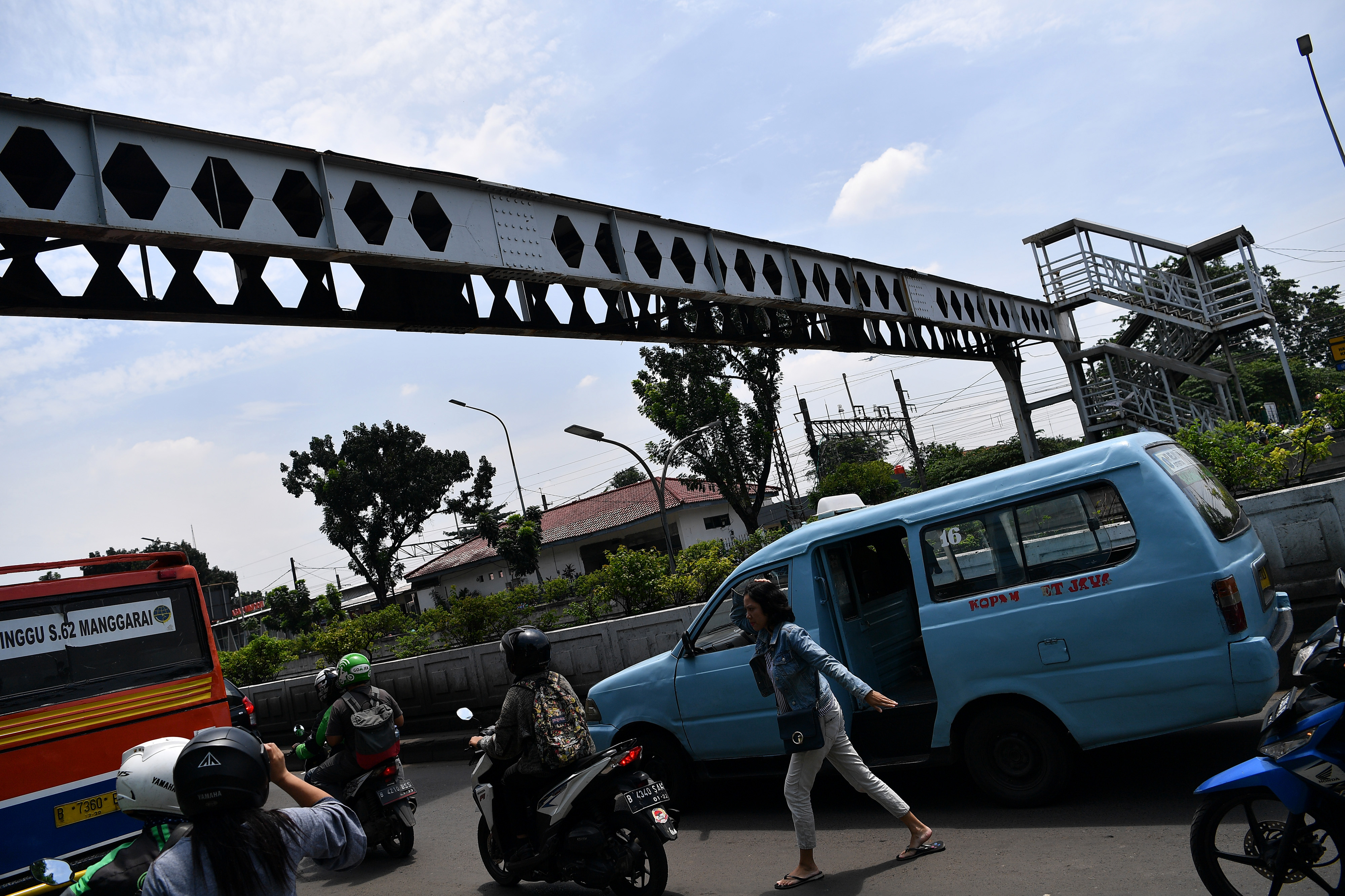 Warga dan pengendara motor melintas di dekat Jembatan Penyeberangan Orang (JPO) yang rusak di Pasar Minggu, Jakarta Selatan.