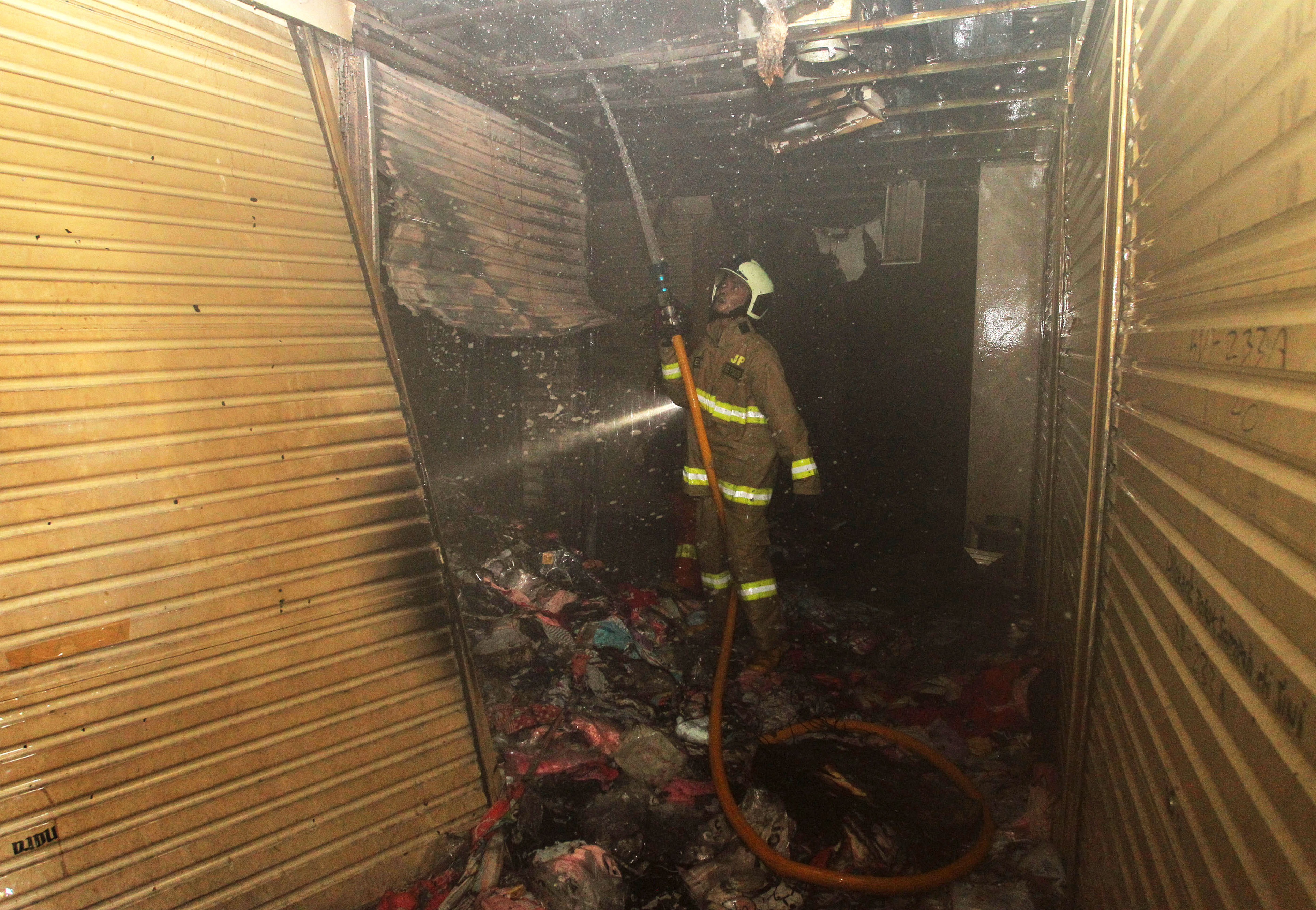 Petugas pemadam kebakaran melakukan pembahasan pada gudang pakaian yang terbakar di Blok C, Pasar Tanah Abang