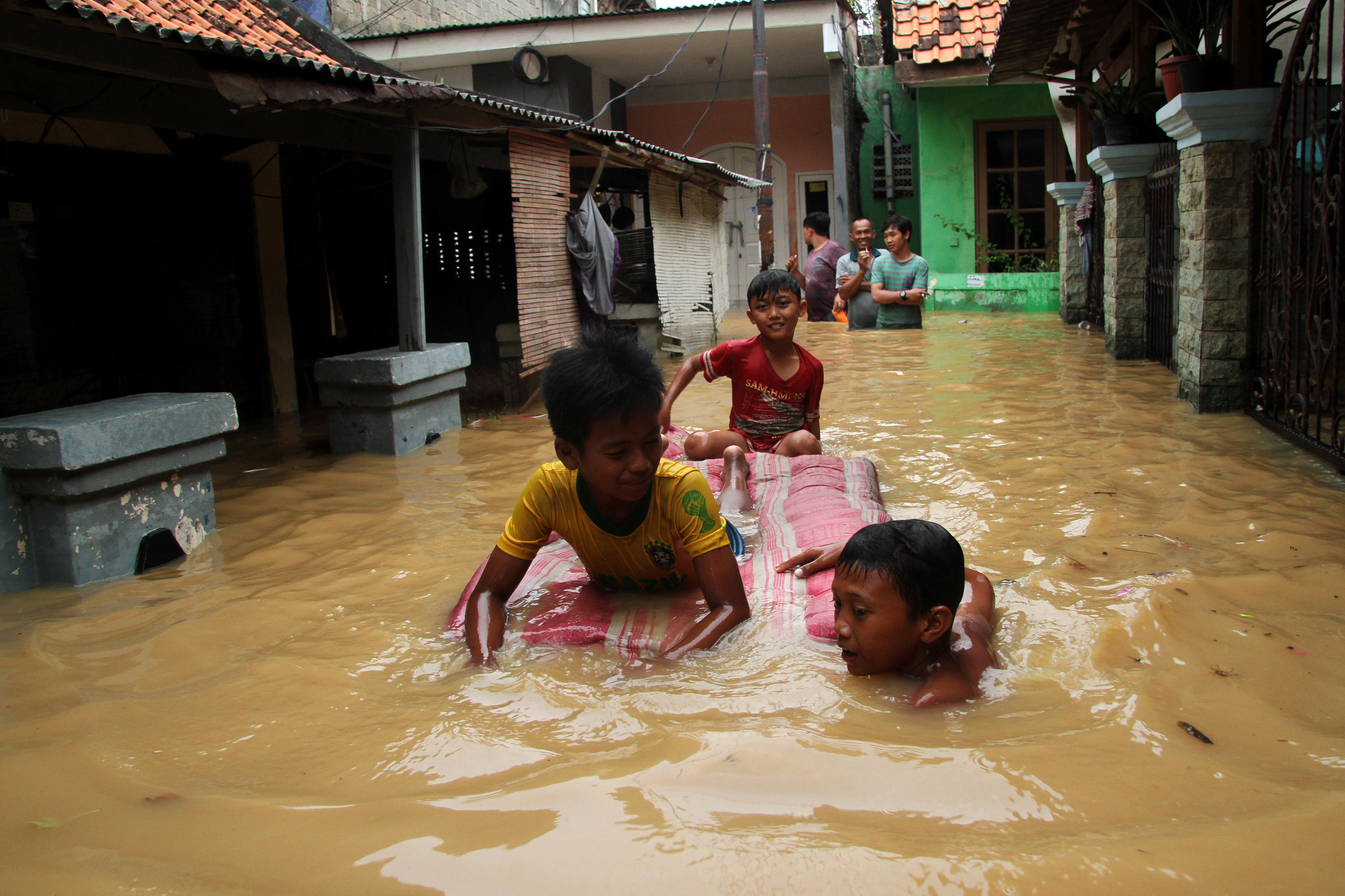 Sejumlah anak bermain air banjir yang merendam kawasan permukiman penduduk Cililitan Kecil, Jakarta, Jumat (26/4/2019)