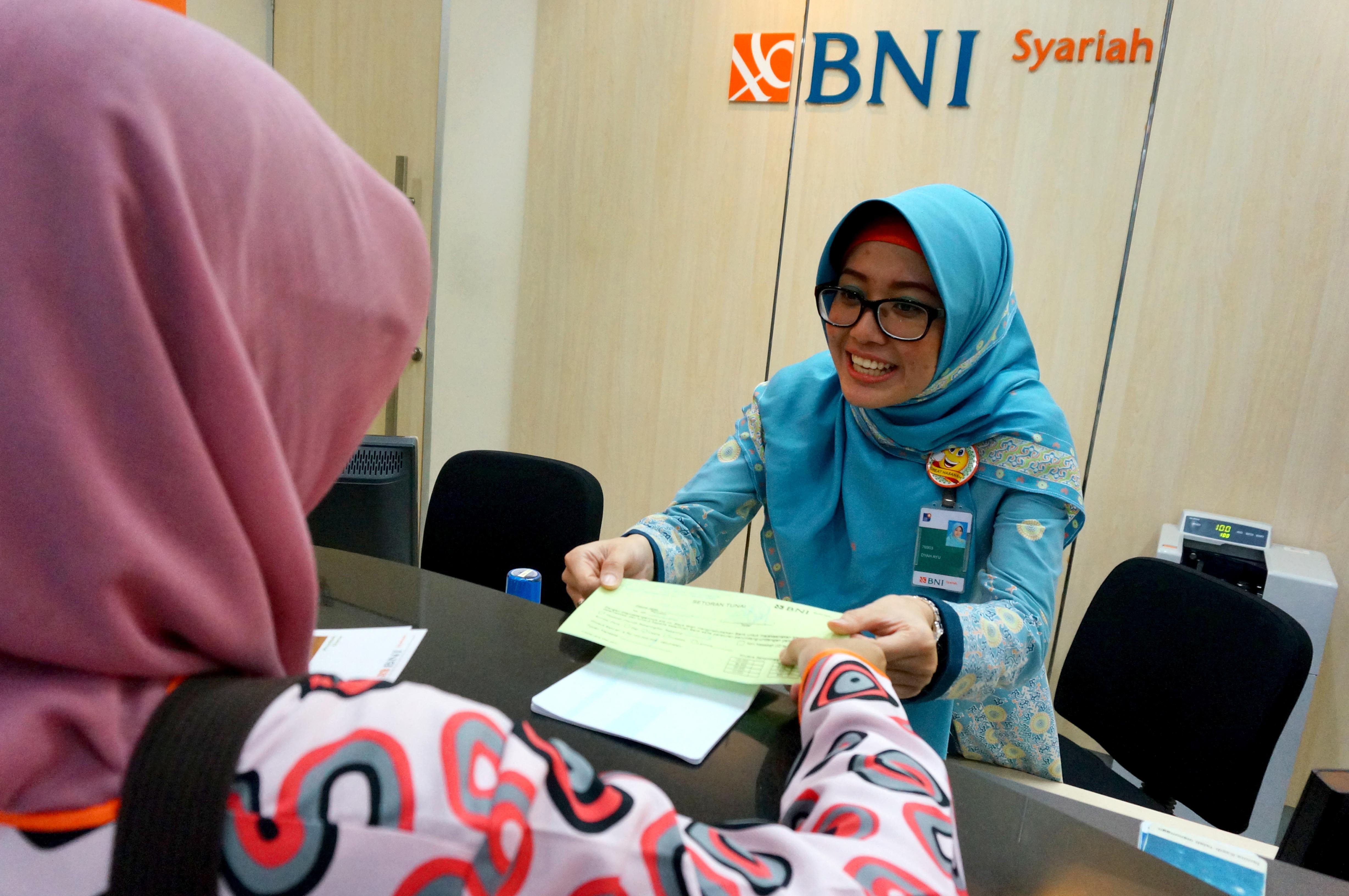 Seorang petugas teller melayani nasabah di Bank BNI 