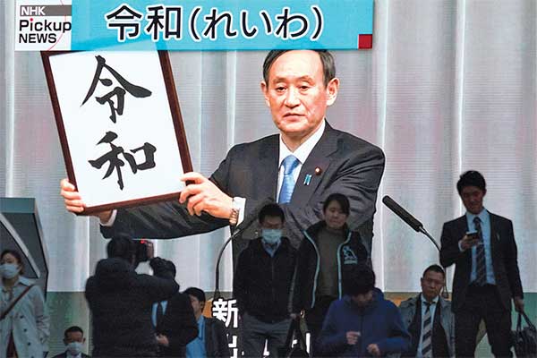 ERA BARU KEKAISARAN JEPANG: Warga berjalan di depan layar yang menayangkan siaran televisi pengumuman karakter kanji untuk menunjukkan nama 