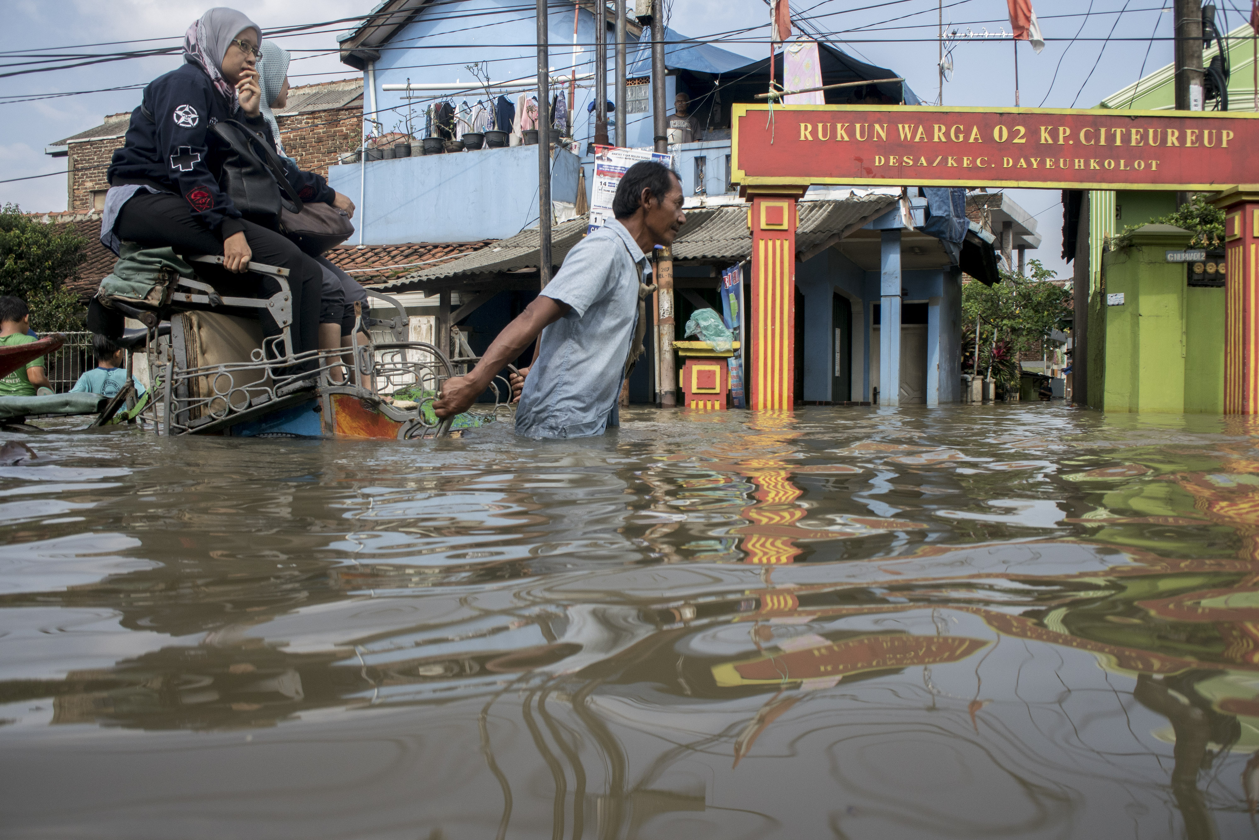 Warga menggunakan becak untuk melintasi banjir luapan Sungai Citarum di kawasan Dayeuhkolot