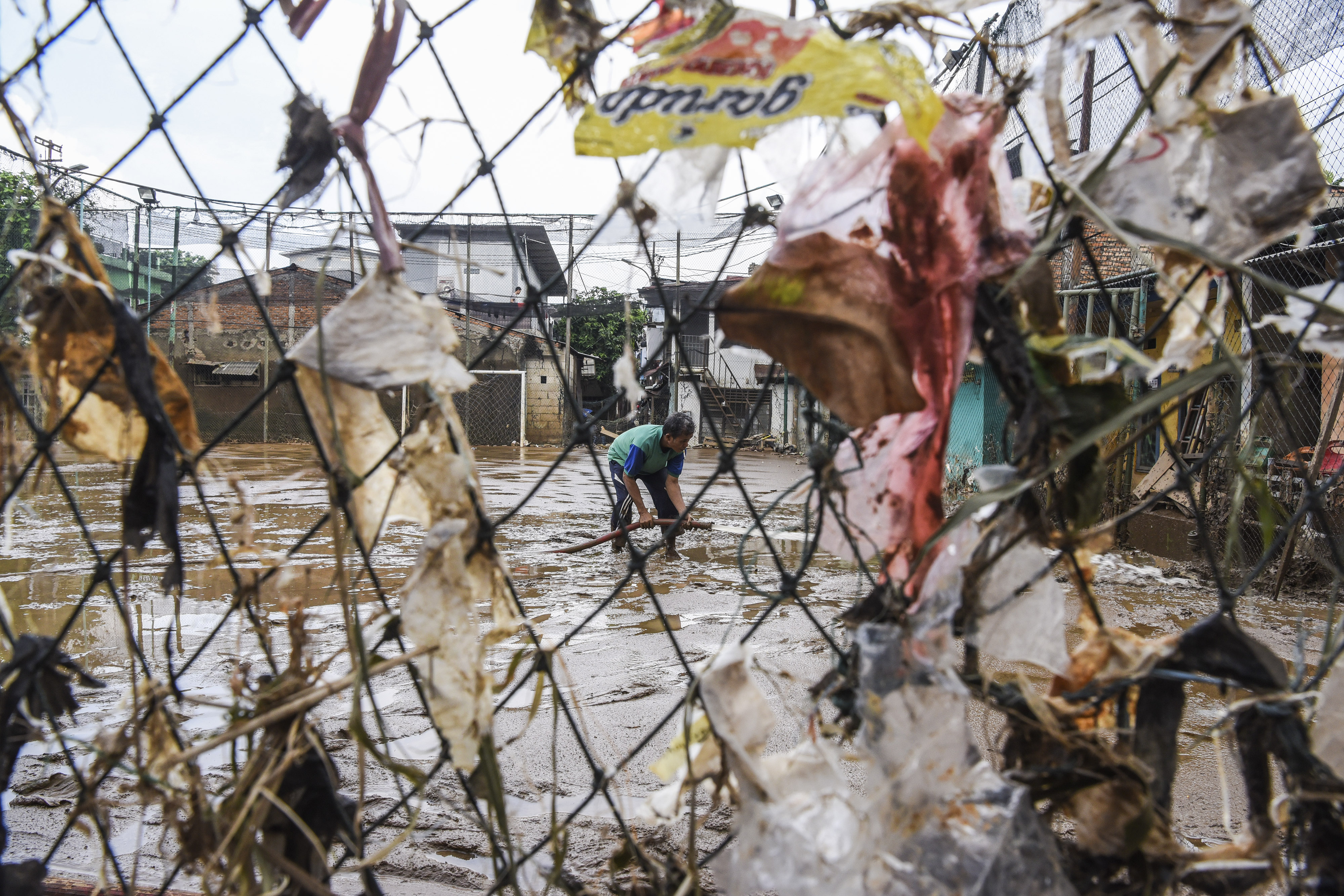 Warga membersihkan lapangan futsal dari endapan lumpur pascabanjir di kawasan Kelurahan Rawajati, Jakarta, Senin (29/4).