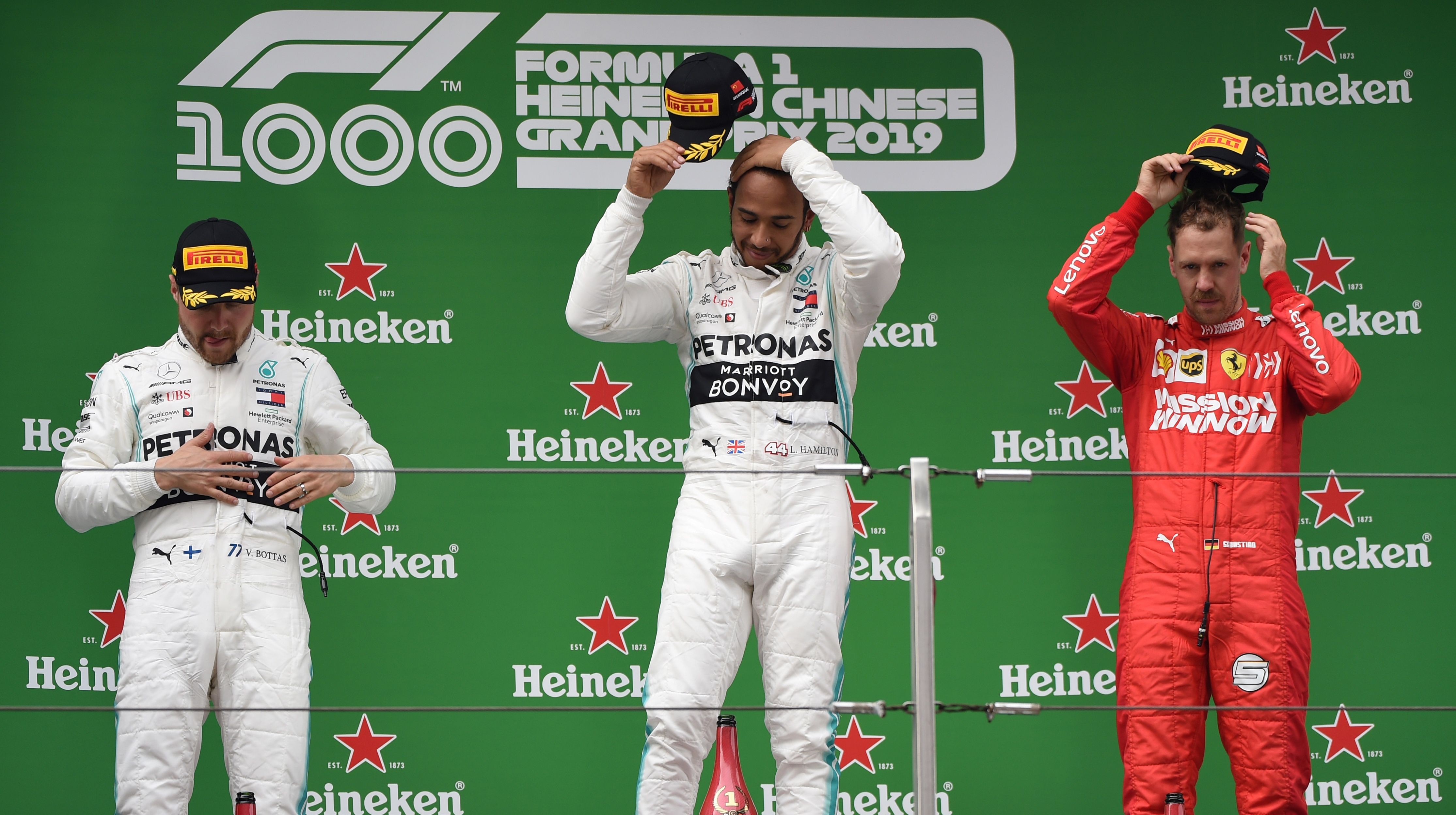  Lewis Hamilton (tengah) berdiri bersama rekan setimnya yang berada di posisi kedua Valtteri Bottas dari Finlandia (kiri) dan Vettel