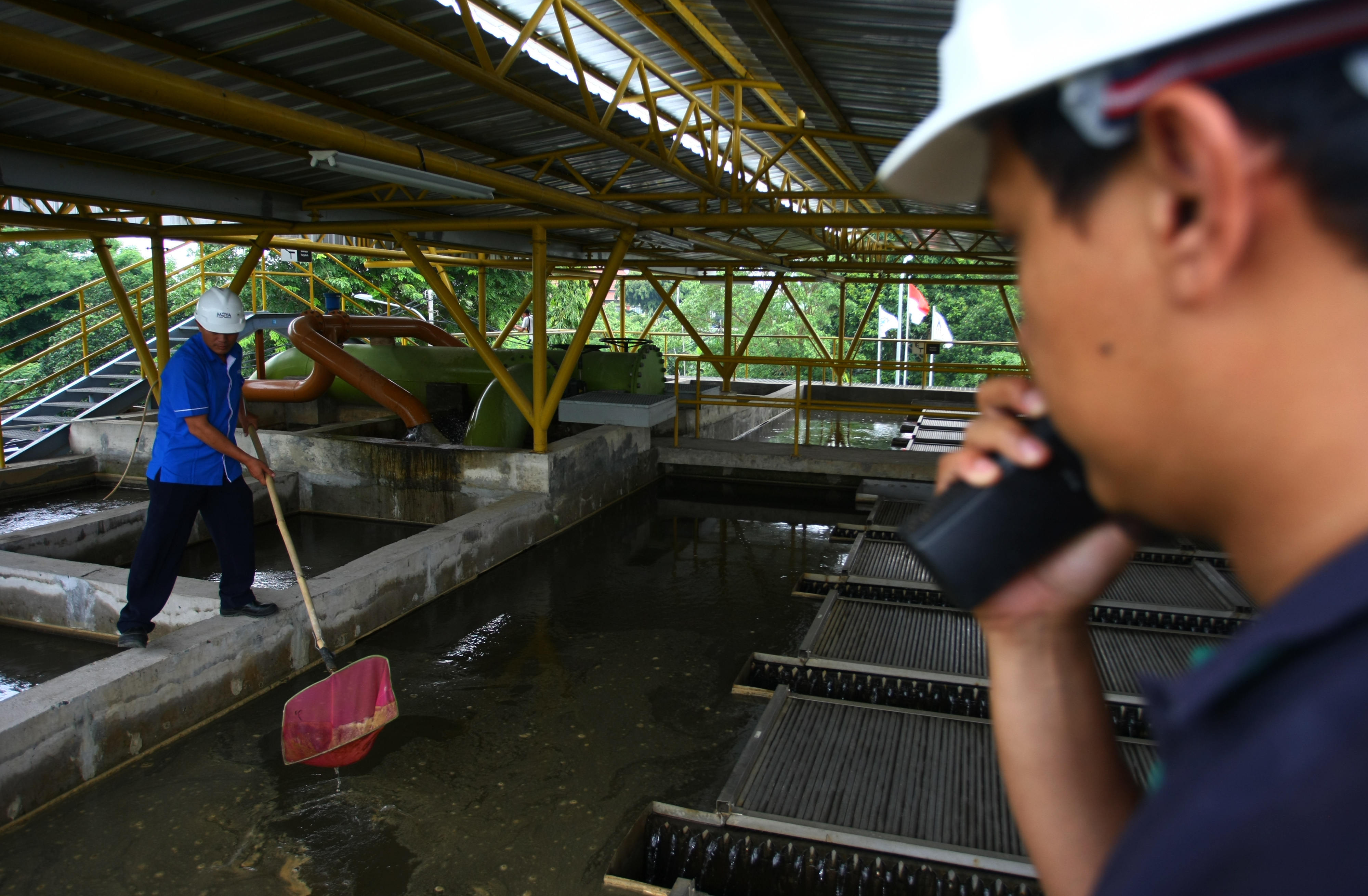 Pekerja dengan menggunakan alat manual mengangkat sedimentasi air baku di kolam penampungan milik PDAM Tirta Benteng Kota Tangerang.