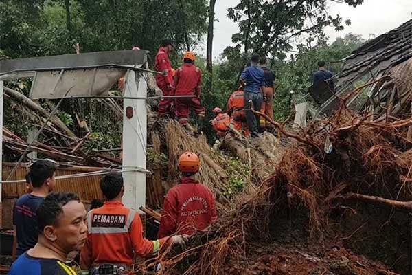 Petugas mengevakuasi korban dan pohon tumbang akibat puting beliung disertai hujan deras yang menerjang Kota Depok, Jawa Barat, pada Senin s