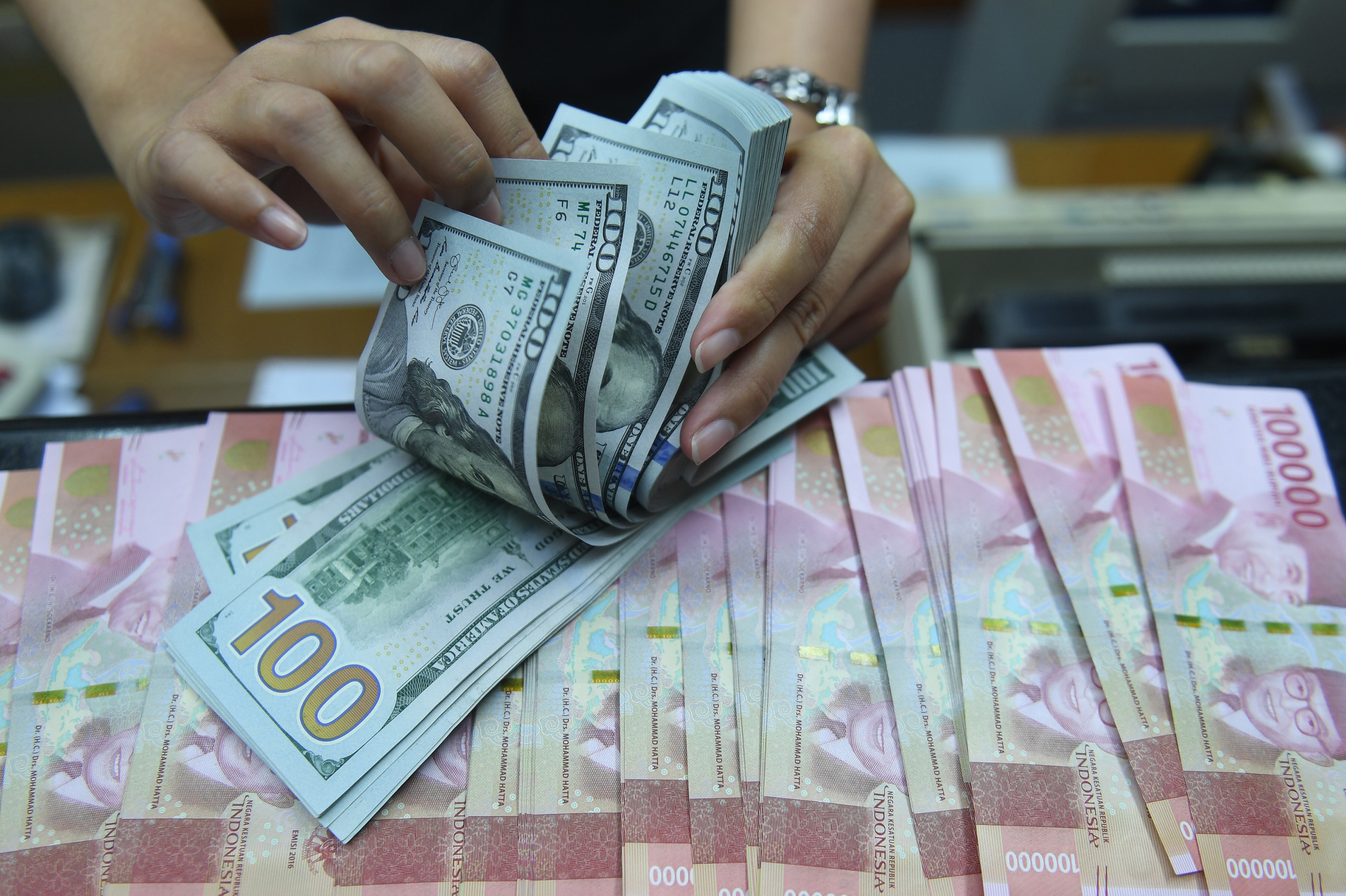 Pekerja menghitung uang Dollar Amerika Serikat dan Rupiah di sebuah tempat penukaran uang di Jakarta