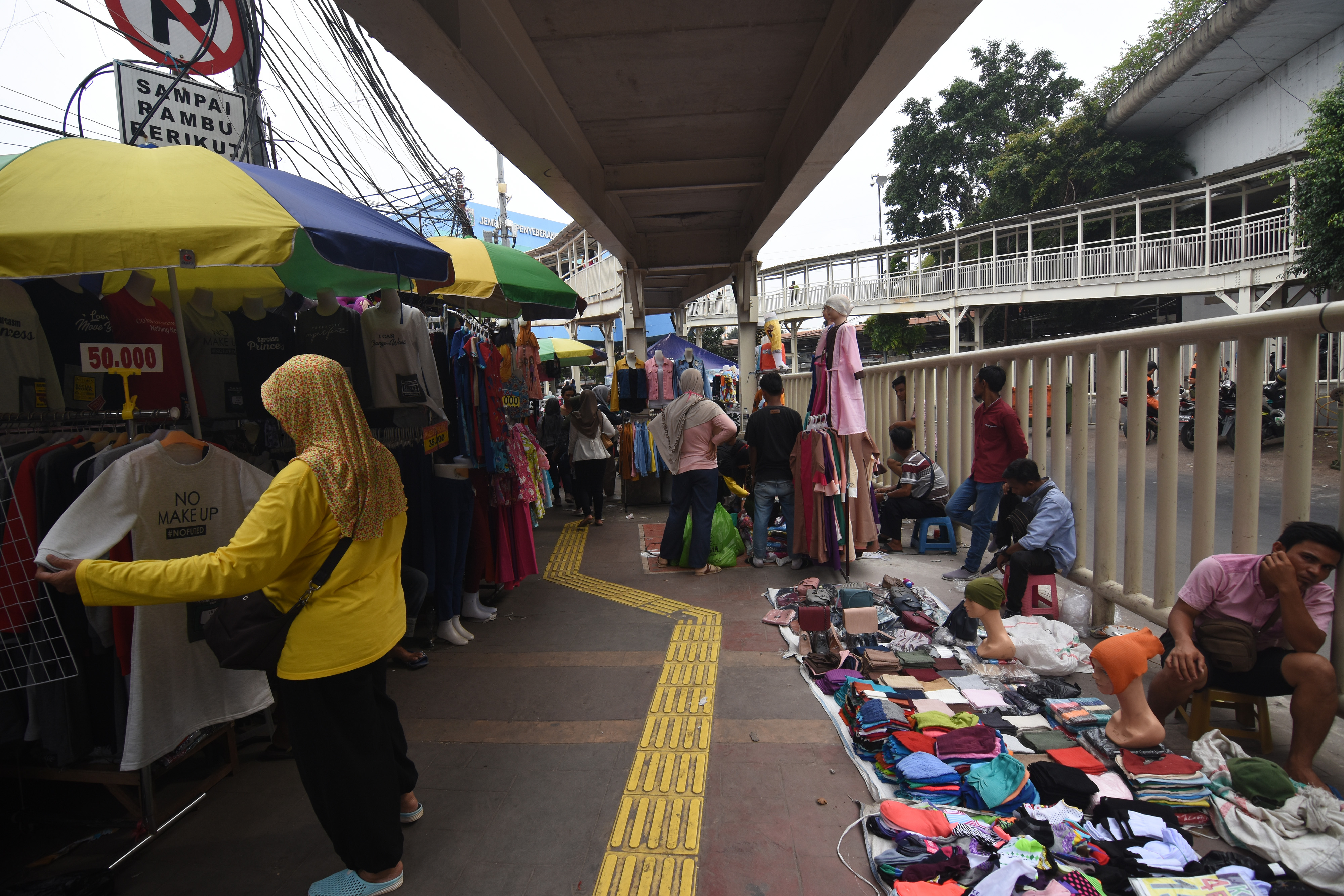 Warga melihat barang dagangan yang dijual pedagang kaki lima (PKL) di trotoar jembatan penyeberangan multiguna (skybridge) Tanah Abang.